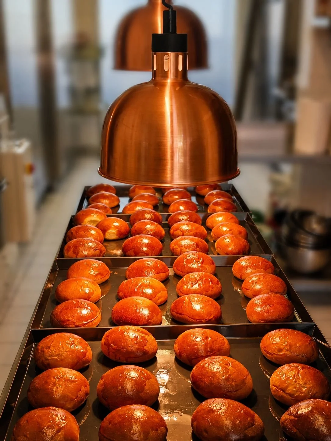 Pane caldi caldi sotto una lampada riscaldante di forma rame, in una cucina.