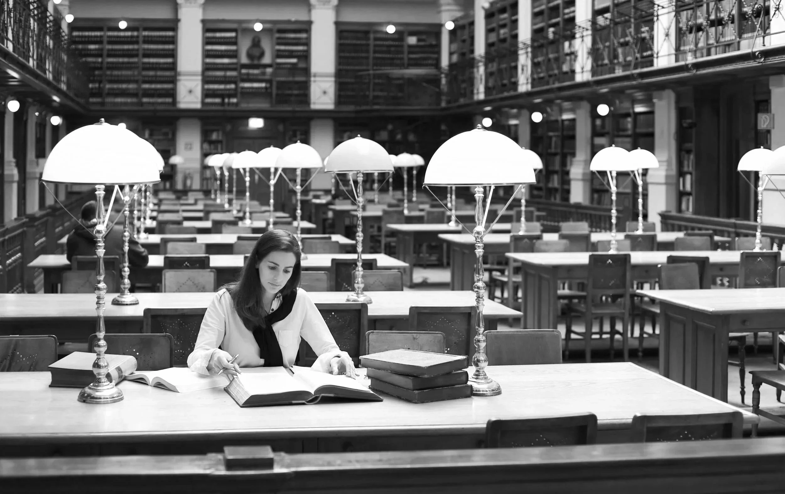 Monochrome view of a student researching inside a prestigious Ivy League university research library, illustrating elite academic mentorship tracks.
