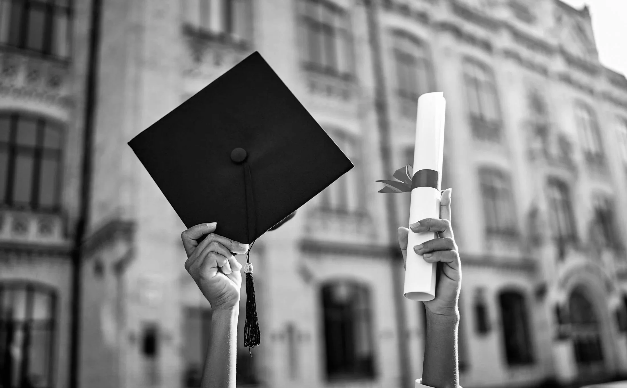Black and white photograph of a graduate holding a graduation cap and diploma, representing elite US university graduate admissions success.