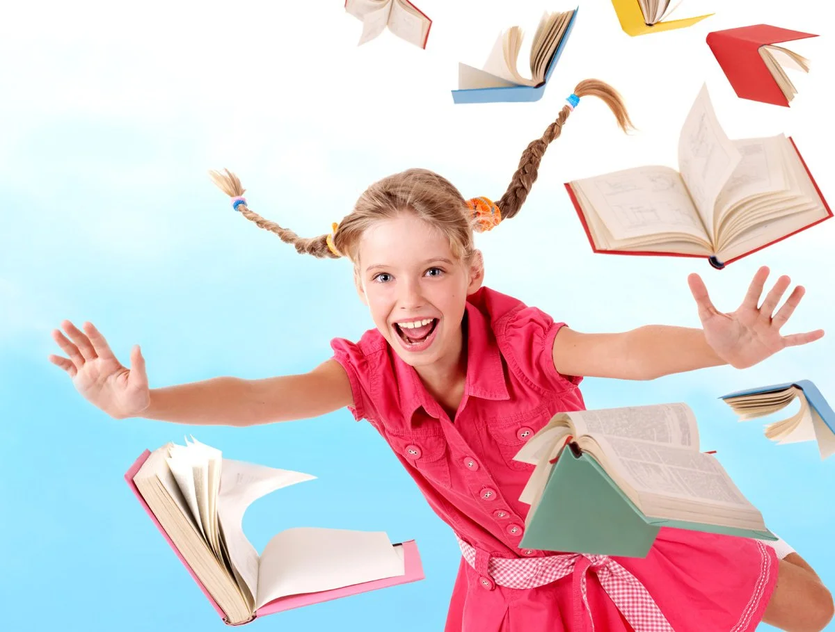 Niña sonriente con trenzas, rodeada de libros abiertos flotando, en un fondo azul claro.