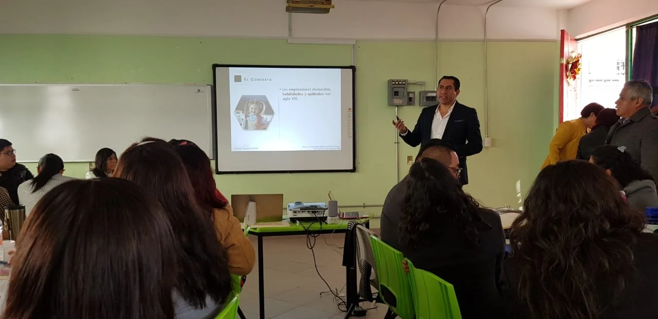 Hombre de traje dando una presentación en un salón con varias personas sentadas.