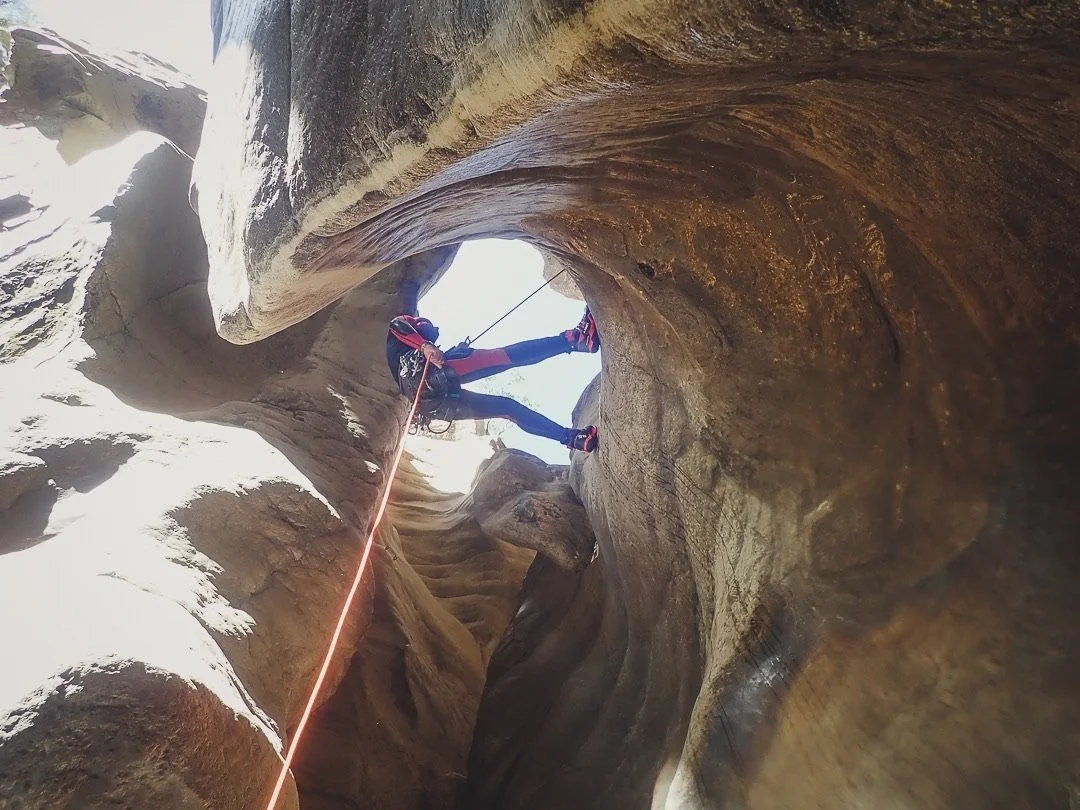  Personas haciendo rappel en un cañón con paredes de piedra.