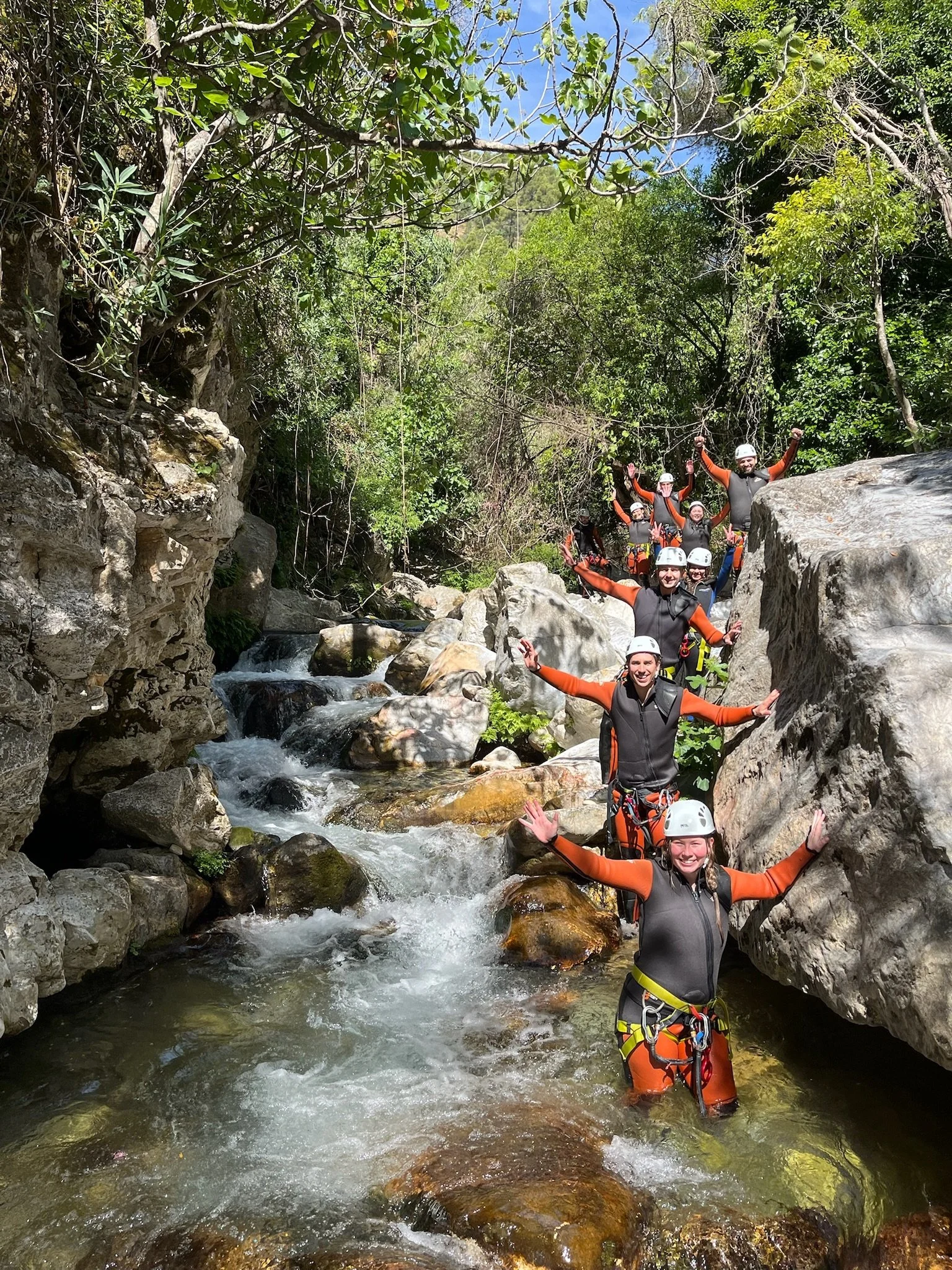 Un grupo de personas con equipo de seguridad haciendo rafting en un río rodeado de rocas y vegetación verde.