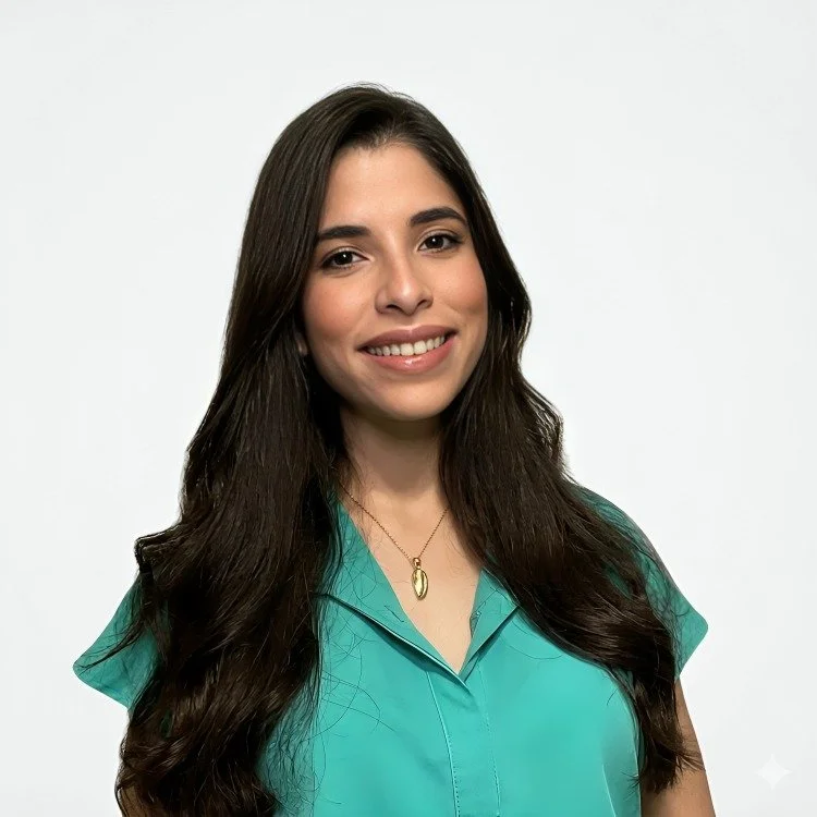 Nurse Natalia Guzman Torres with long dark hair, wearing a turquoise blouse and a gold necklace, smiling against a plain white background.
