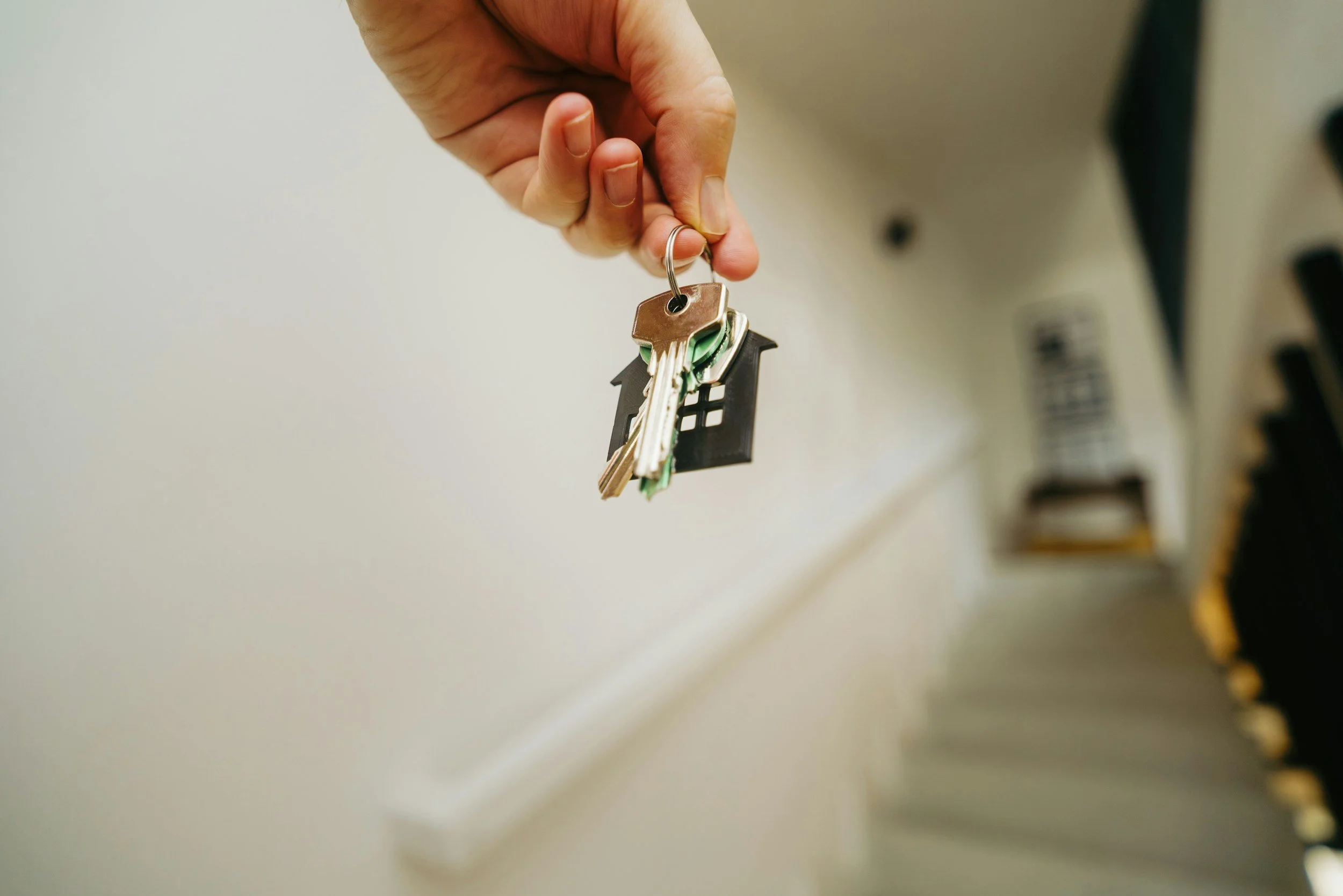 Close-up of a hand holding a keyring with house-shaped keychains and keys.