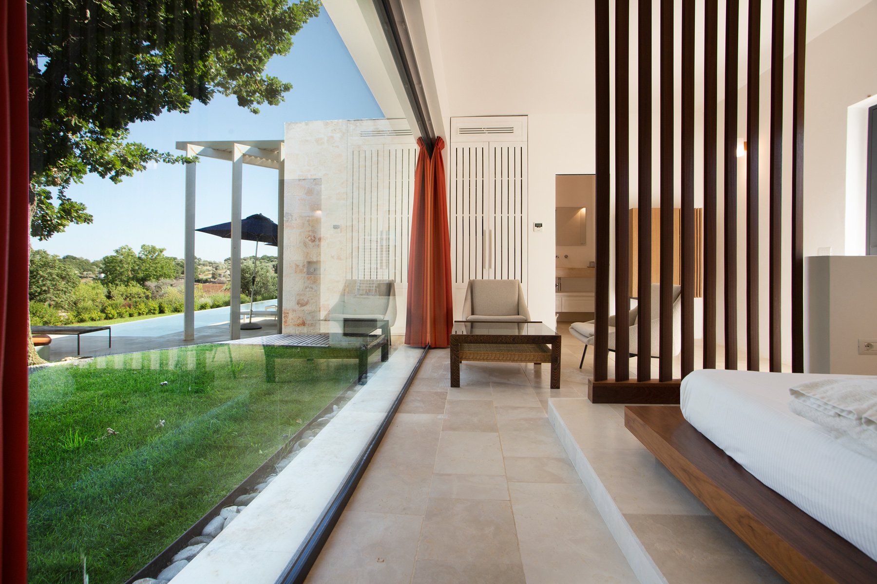 Chambre moderne avec vue sur le jardin et une terrasse extérieure, mobilier en bois clair et ambiance lumineuse.