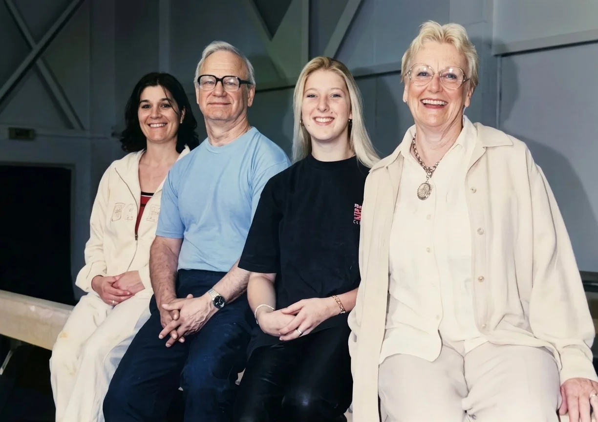 A group of four smiling people sitting together indoors, with a modern background.