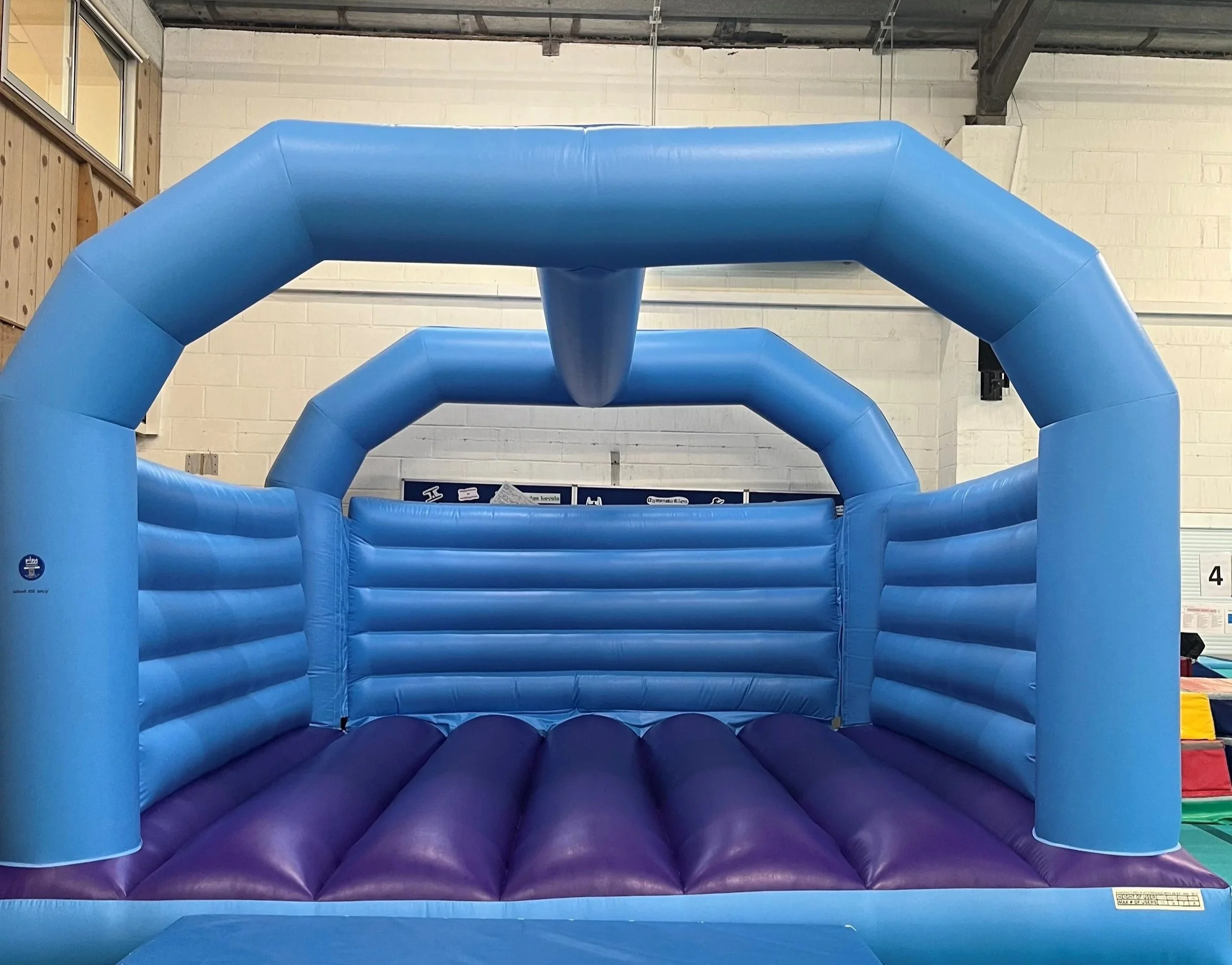 Indoor inflatable obstacle course with blue and purple sections.