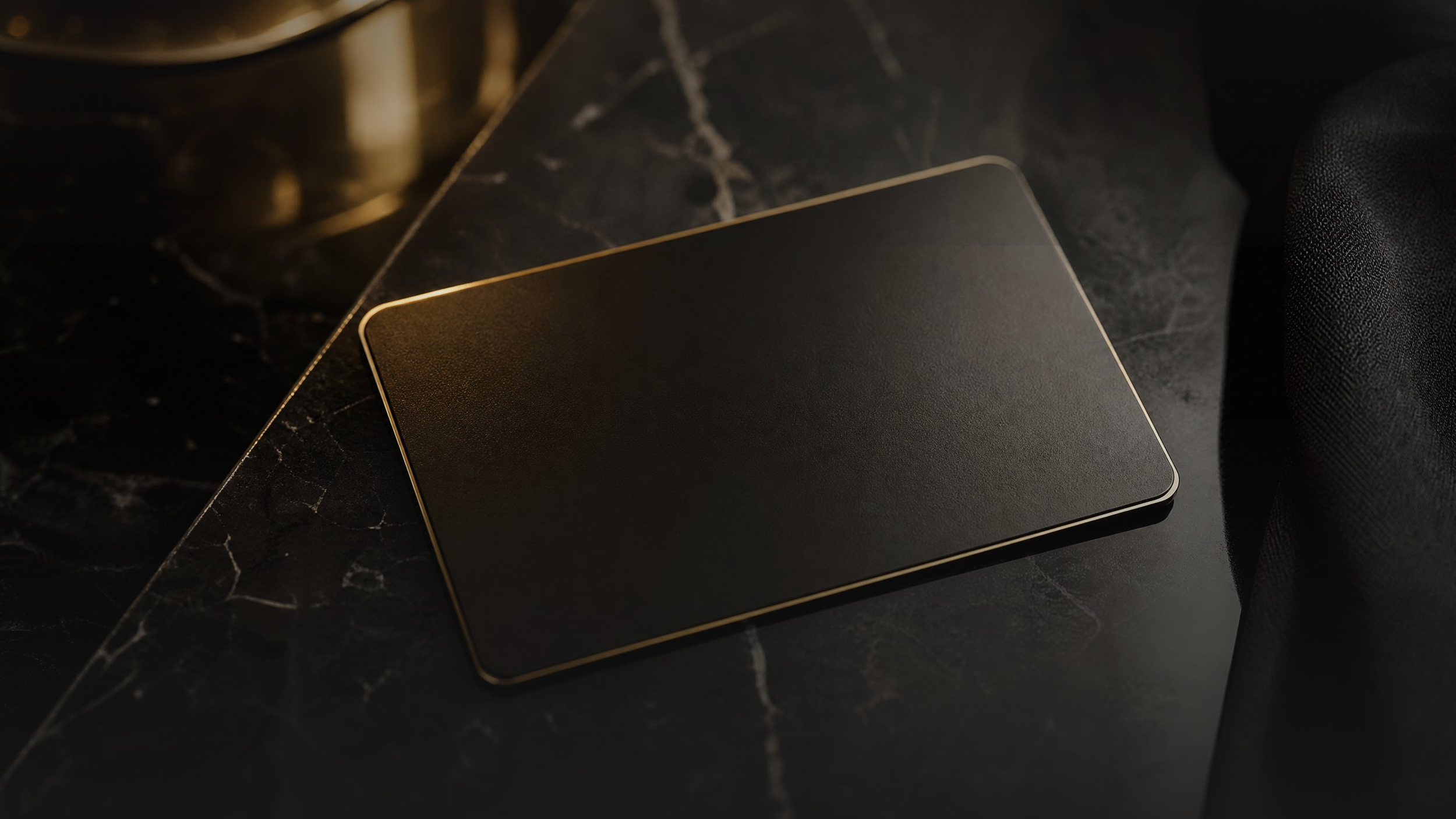 A black rectangular object with rounded edges and a metallic border, lying on a dark marble surface.