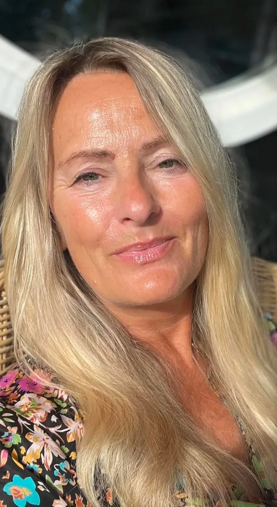En smilende kvinde med langt blondt hår, der ser afslappet ud.