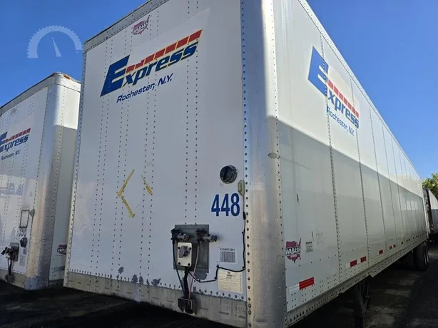 White semi-trailer truck with Express Logistics logo and 'Rhinebeck, N.Y.' label, parked outdoors under a blue sky.