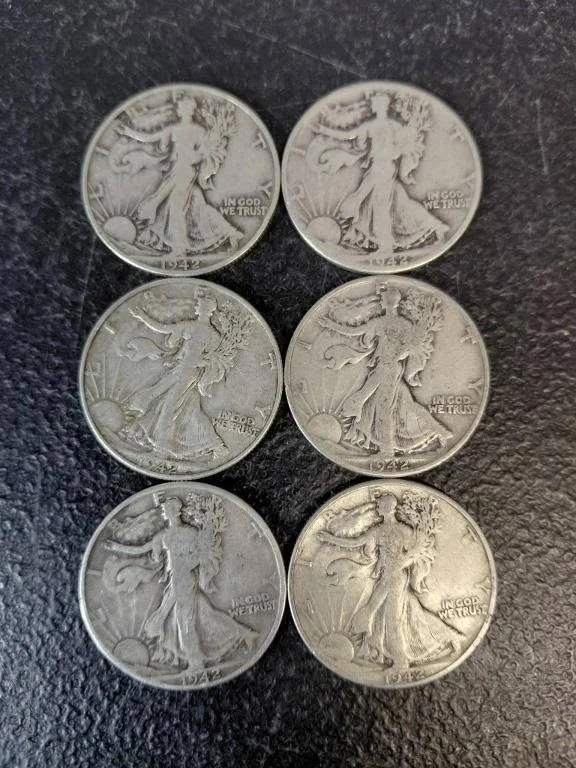 Six vintage Walking Liberty half dollar coins arranged on a dark surface.
