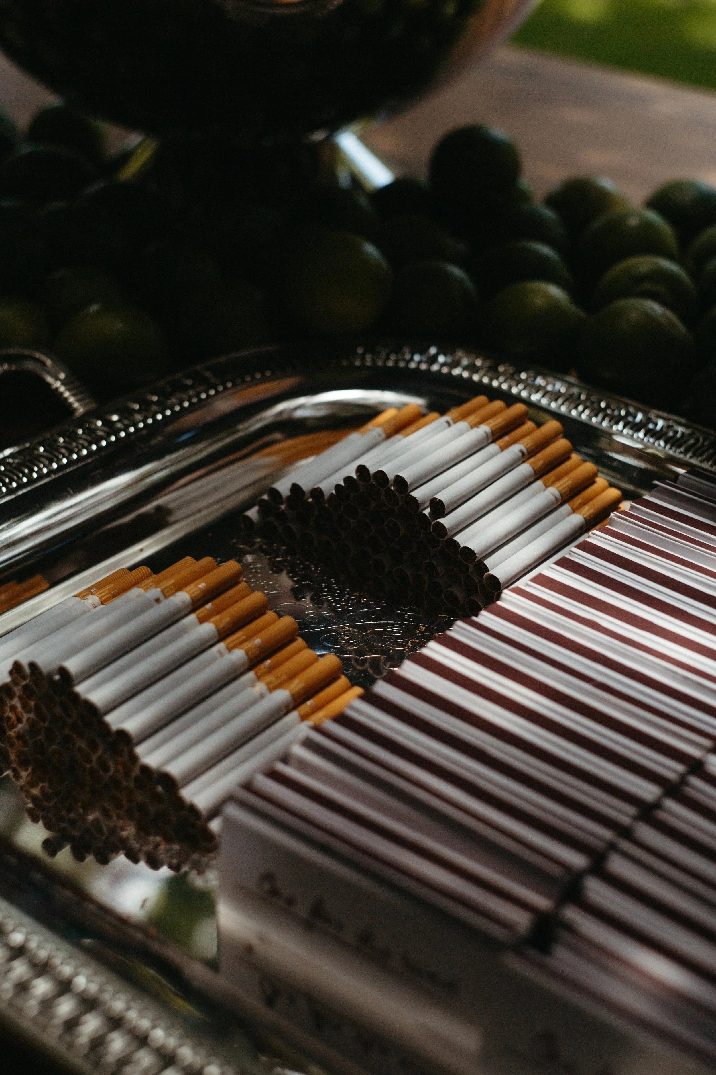Close-up of a tray of cigarettes with a bunch of limes in the background.