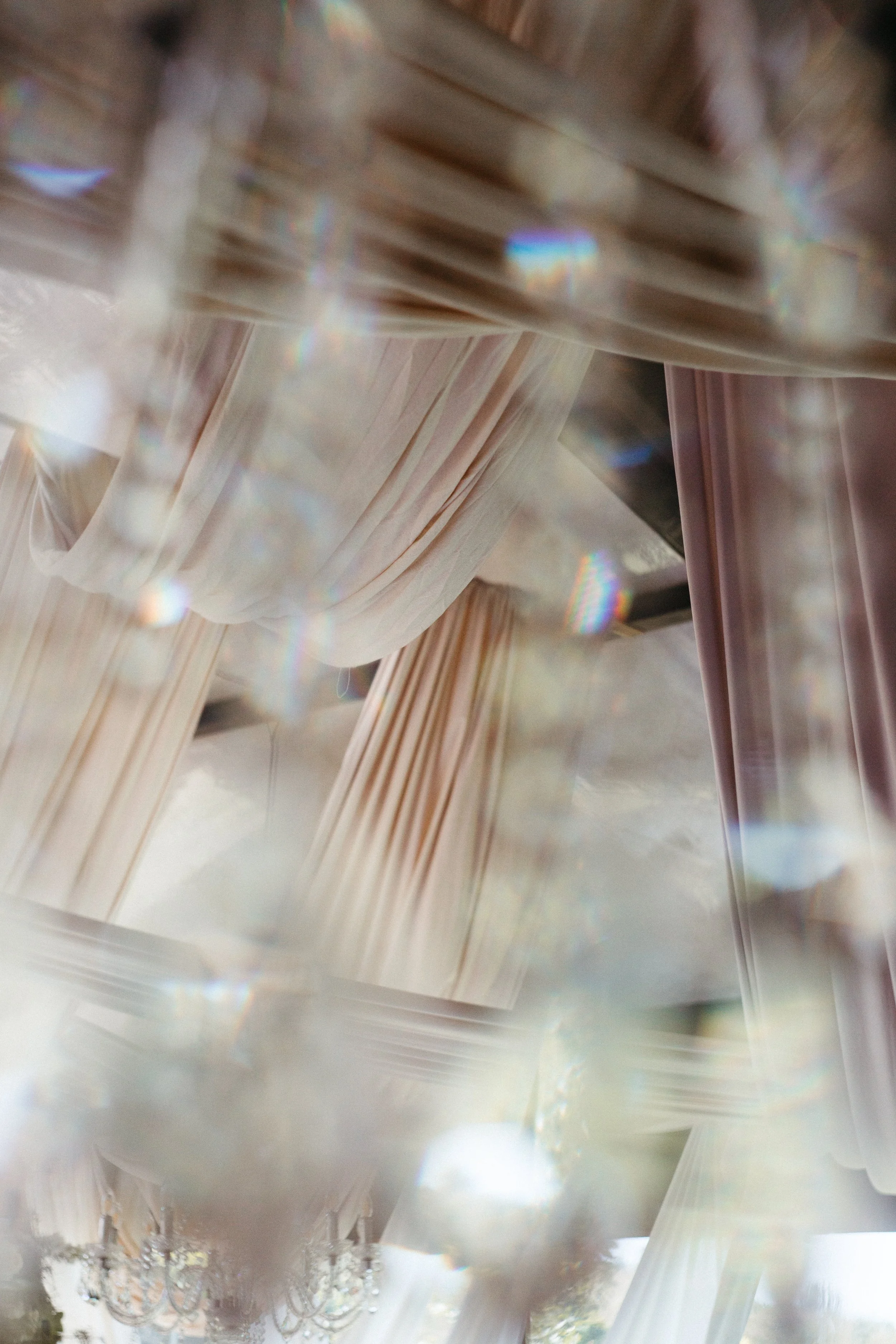 Close-up of a light-colored fabric with a pattern of multi-colored iridescent sequins, possibly part of a dress or decorative textile.