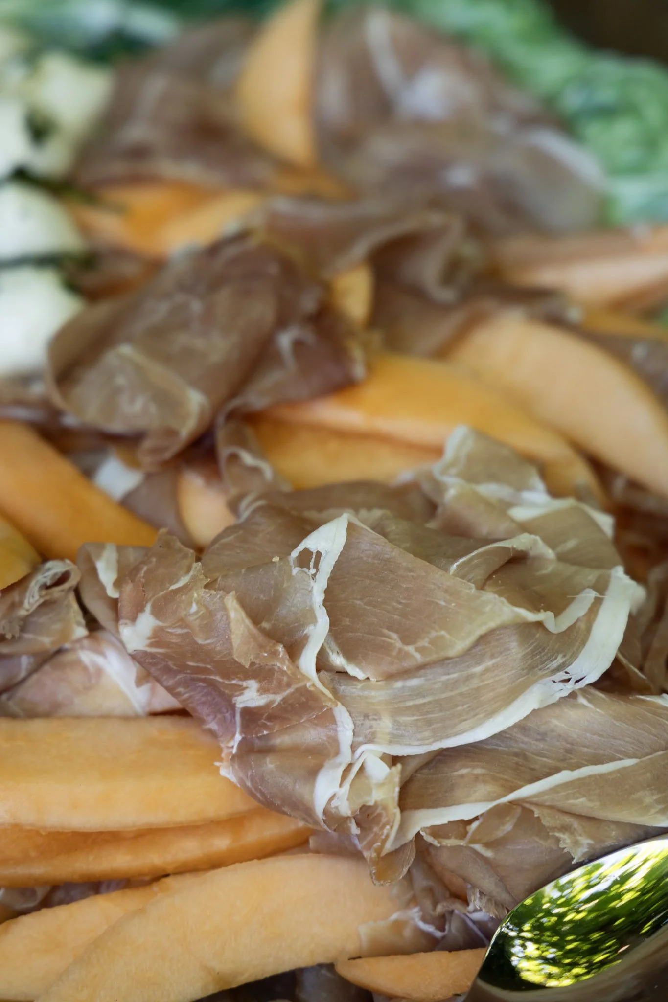 Assorted sliced cured meats and cheese on a platter, garnished with green herbs.