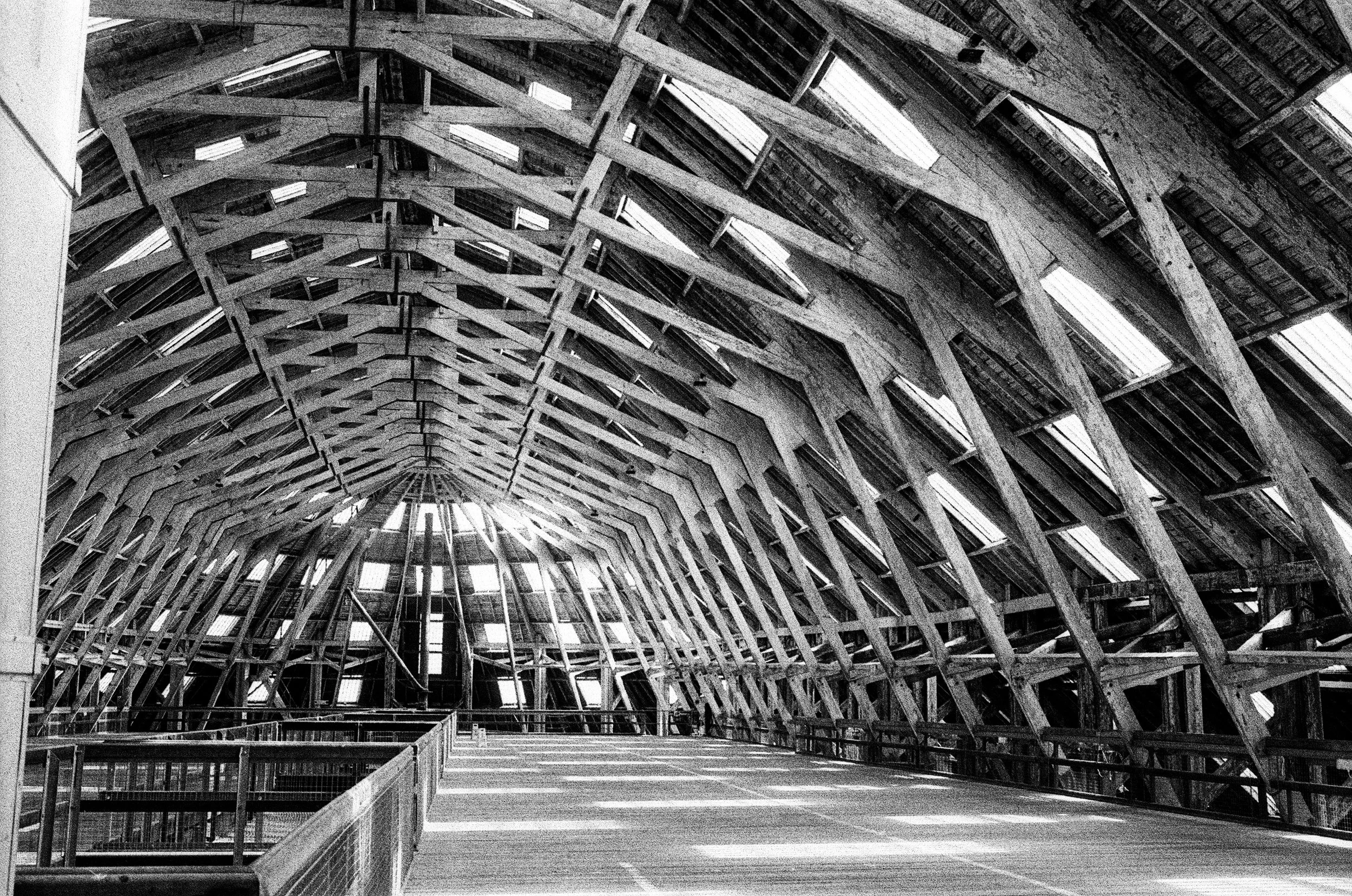 Construction site with an arched metal framework and windows, black and white image.