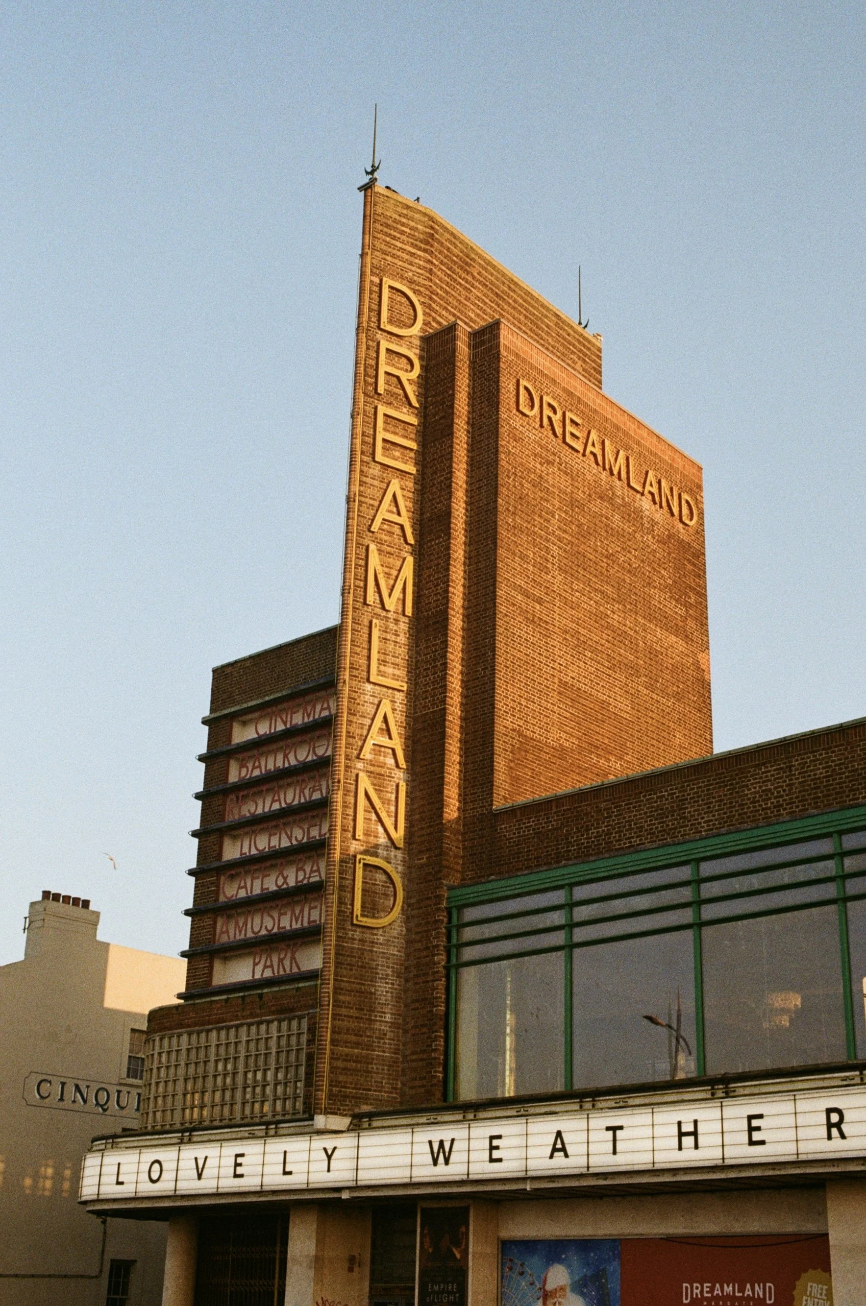 The image features the historic Ethel Barrymore Theater building with standout brick architecture, vertical and horizontal signage including the words "DREAMLAND," theater marque sign reading "LOVELY WEATHER," and other signage indicating a cinema, b