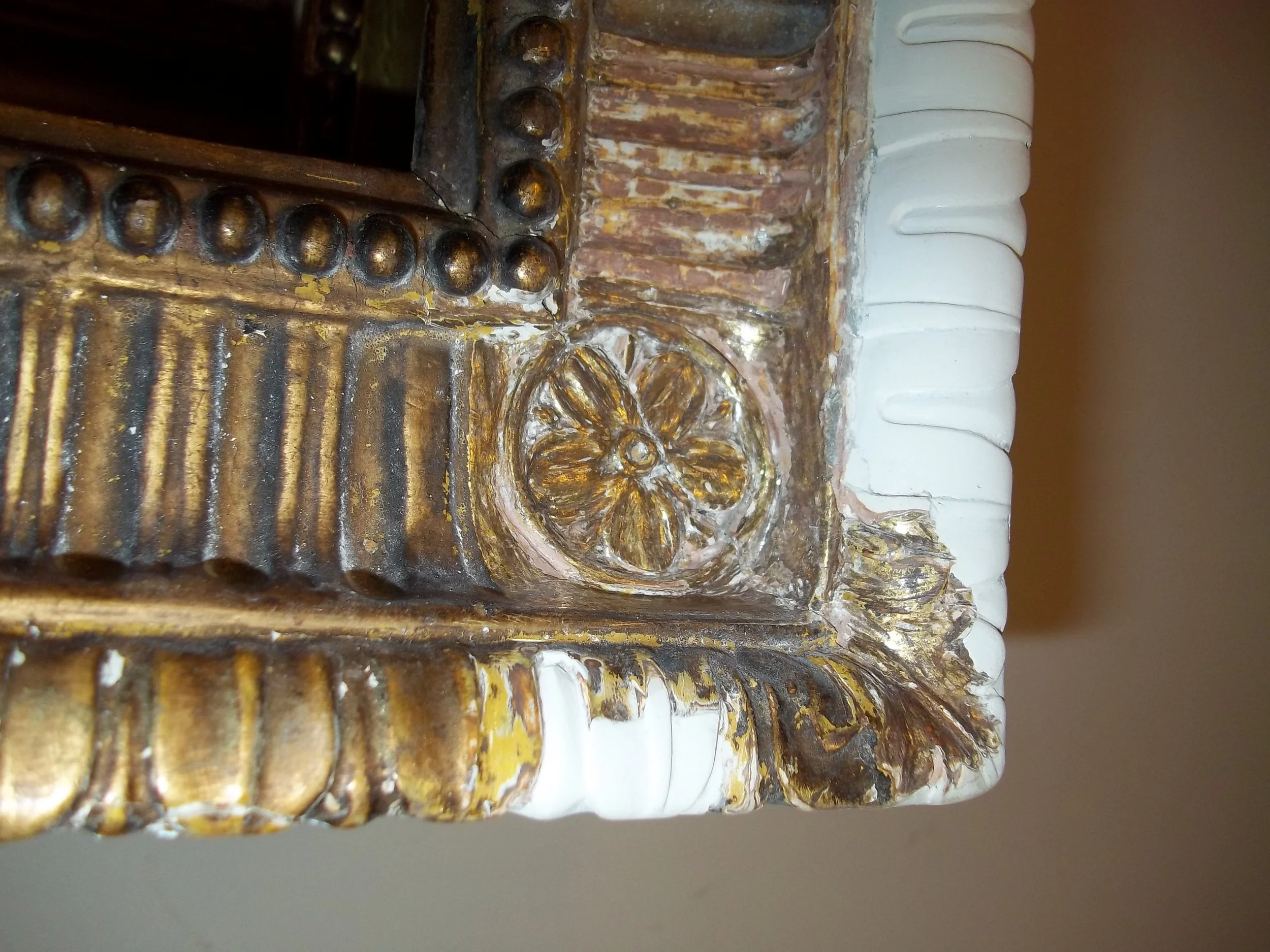 Close-up of an ornate piece of furniture with gilded, carved details and white decorative elements.