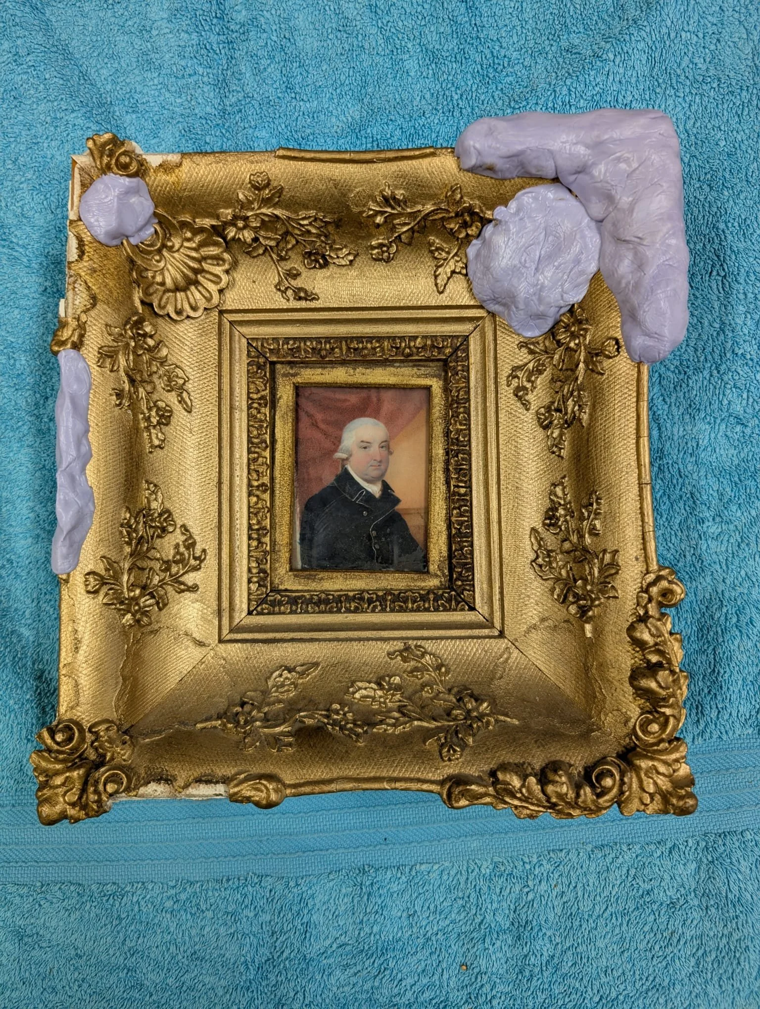 A framed portrait of George Washington with ornate gold decoration on a blue textured background.