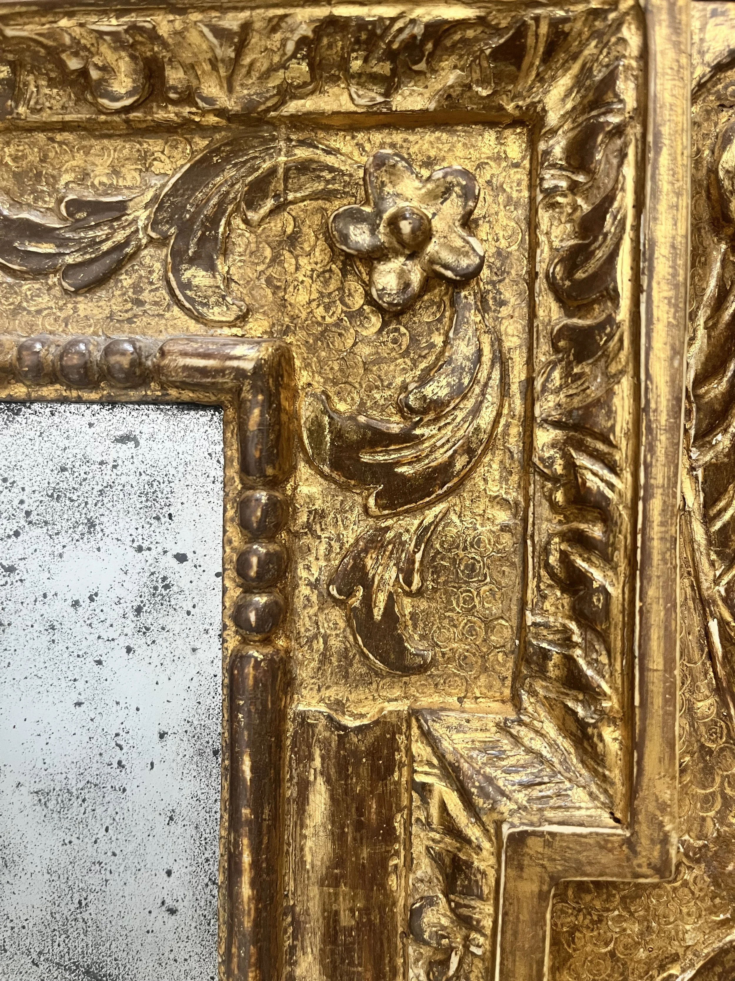 Close-up of an ornate, antique gold picture frame with intricate carved floral and scroll patterns.