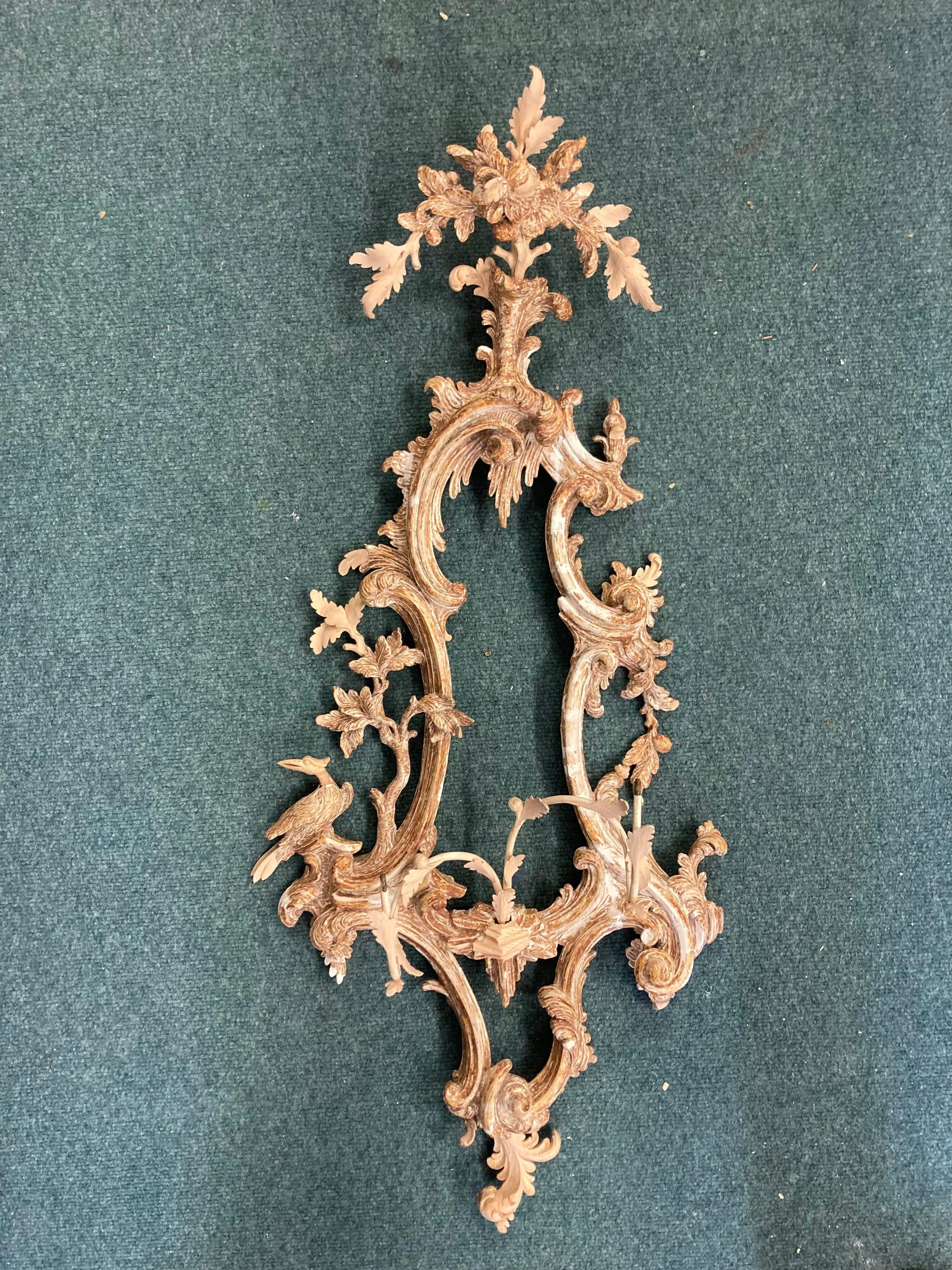 Wooden ornate wall decoration with intricate carvings of leaves, flowers, and birds on a green fabric background.