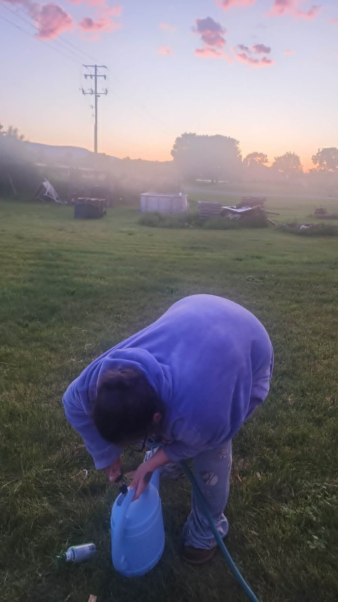 woman watering the Heathen Farms garden at sunrise in Newburg, Pennsylvania