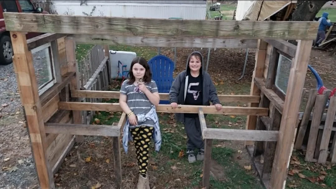 Children helping build a reclaimed-wood farm stand at Heathen Farms