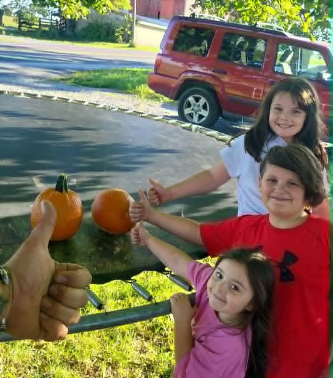 Heathen Farms children showing two small pumpkins harvested from the family garden