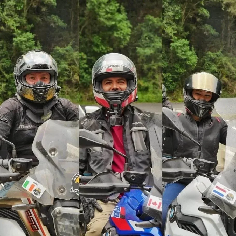 Three motorcyclists wearing helmets and riding gear, smiling while sitting on their adventure bikes in a  Wilderness, on the Garden Route, South Africa WC