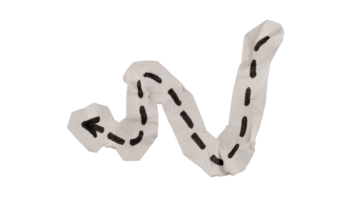 A white tissue paper folded into the shape of a winding road with black dashed lines and arrows, on a white surface with a red background.