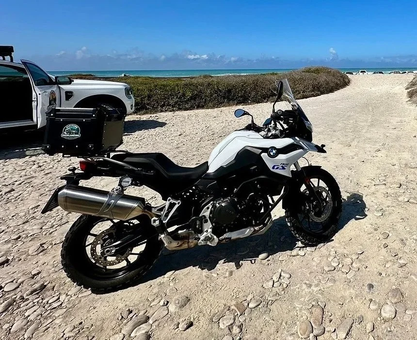 White low profile BMW F800GS adventure motorcycle rental parked on Scarborough beach in Cape Town, South Africa