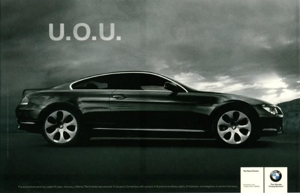 A black BMW coupe car parked outdoors against a cloudy sky, with the text 'U.O.U.' in the upper left corner.