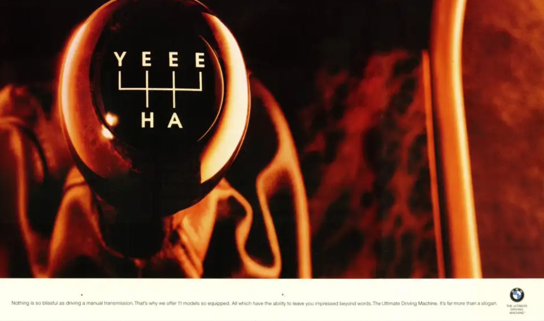 Close-up photograph of a BMW car gear shift knob with a fiery background.