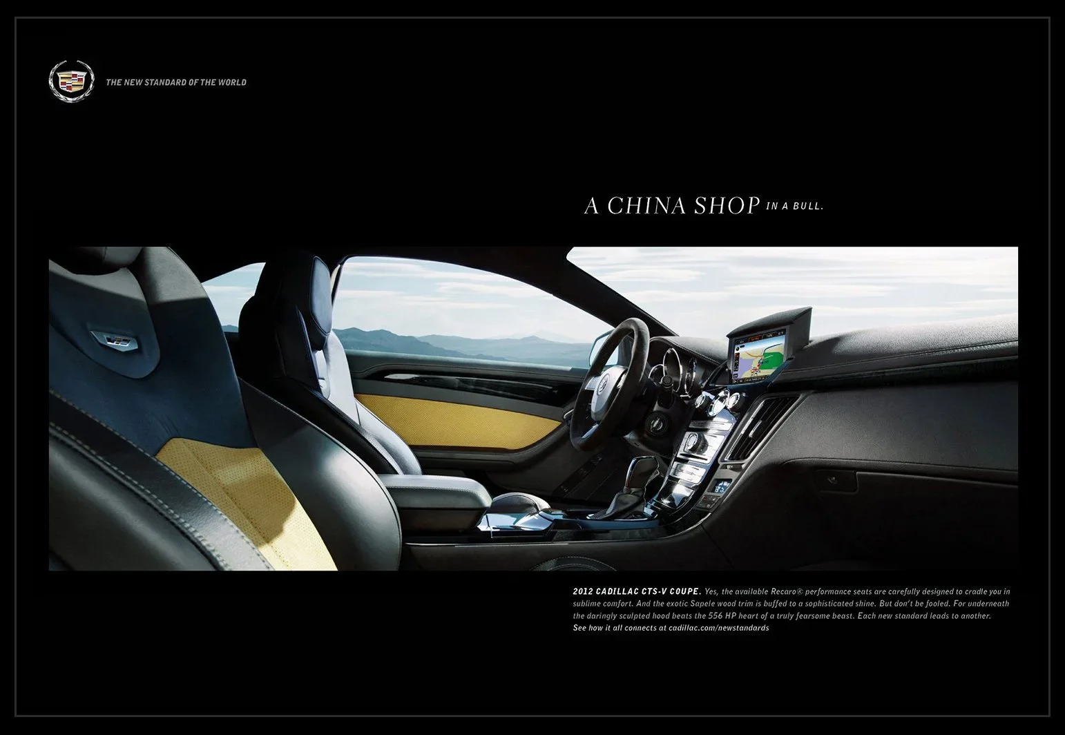 Inside view of a 2012 Cadillac CTS-V Coupe showing leather seats with yellow trim, dashboard with navigation system, and a scenic mountain landscape outside through the windshield.