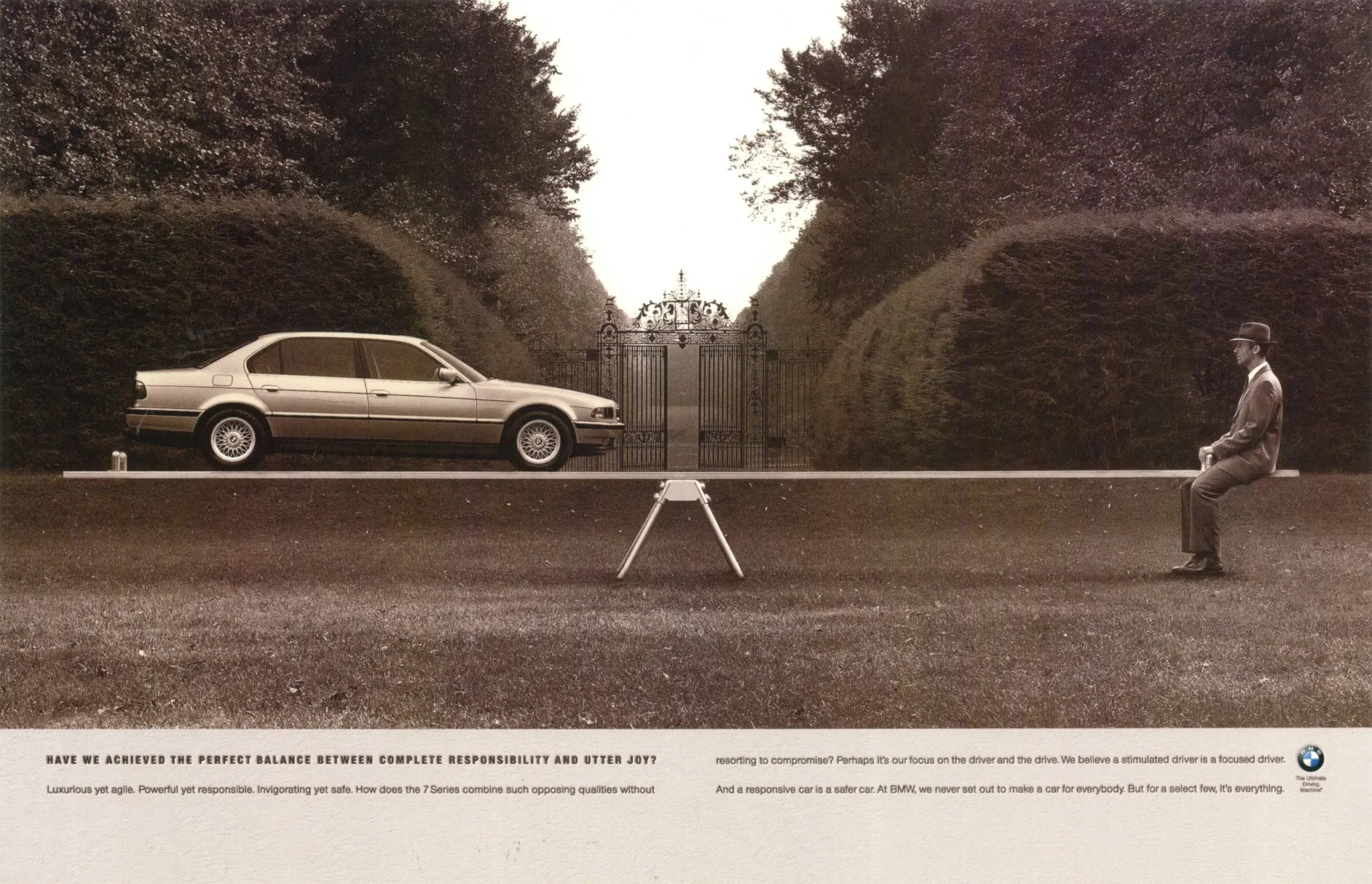 A vintage car is balanced on a seesaw with a man sitting on the right side. The man is dressed in a suit and hat, and the setting appears to be outdoors near a large ornate gate, surrounded by symmetrical hedges or trees. The scene is in black and white, with a caption below discussing the balance between responsibility and joy, featuring the BMW logo.