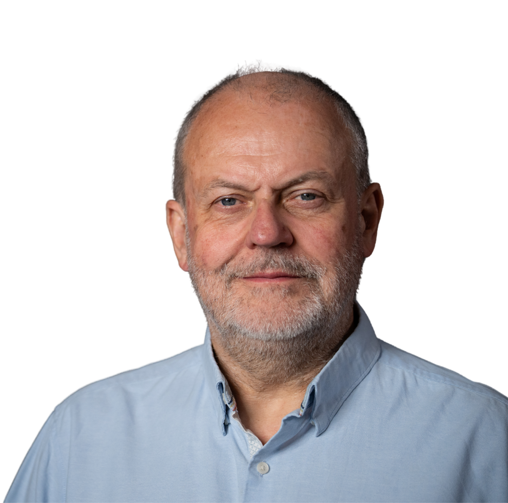 A middle-aged man with blue eyes, gray beard, and mustache, wearing a light blue collared shirt, smiling softly against a black background.