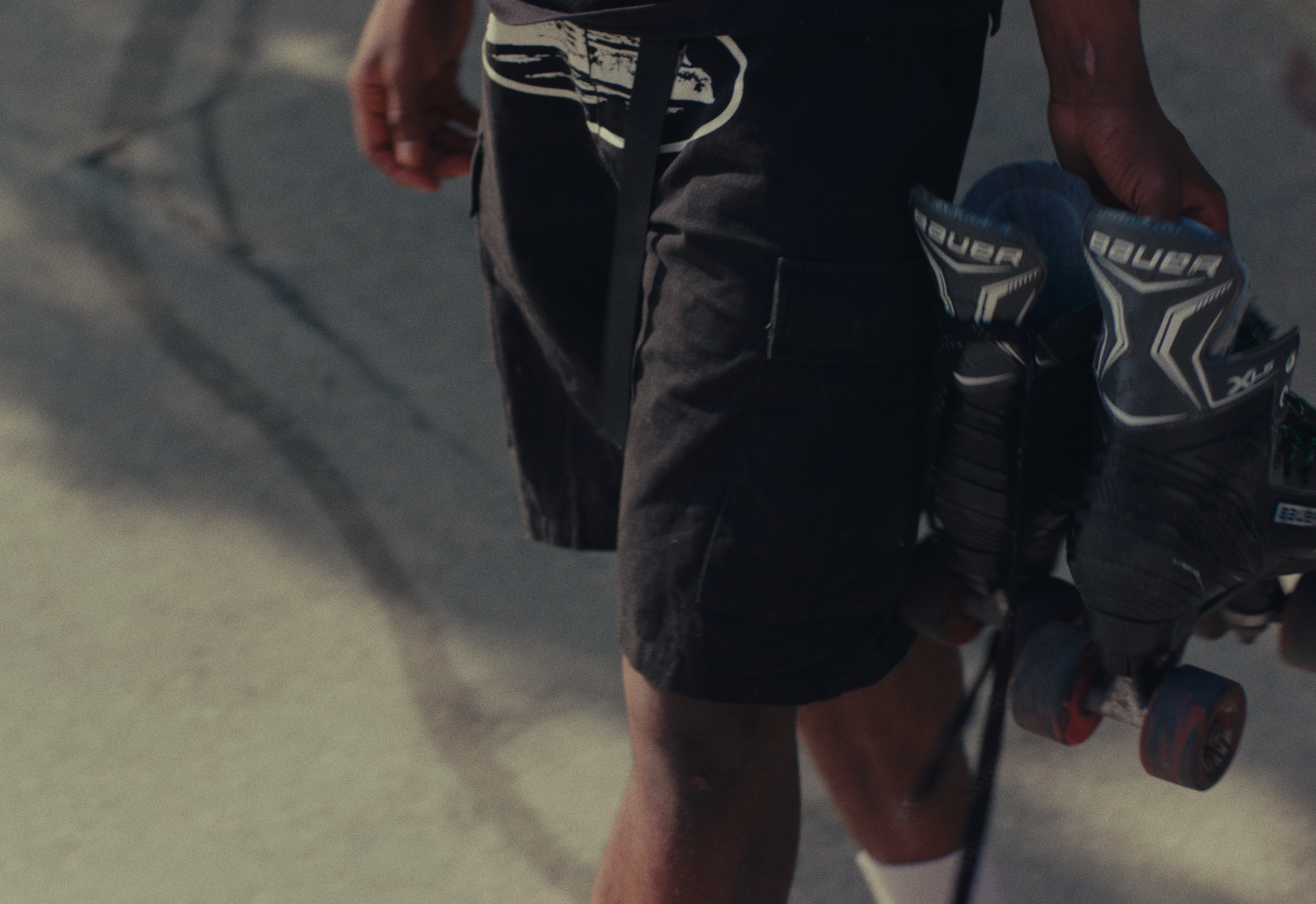 A person in sports gear holding a pair of hockey gloves in their right hand, with a focus on their midsection and arms.