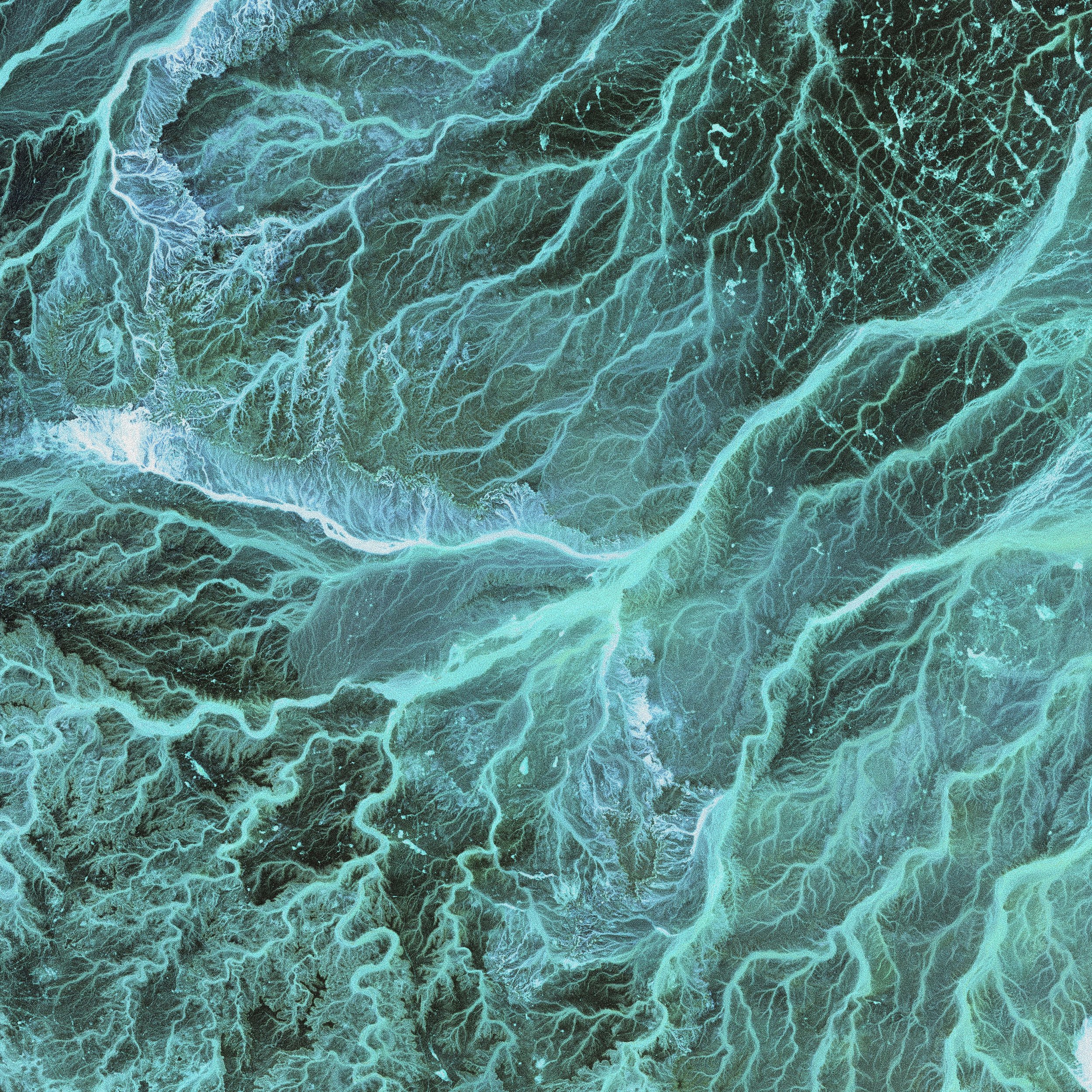 An aerial view of a river delta with branching waterways in shades of blue and green.