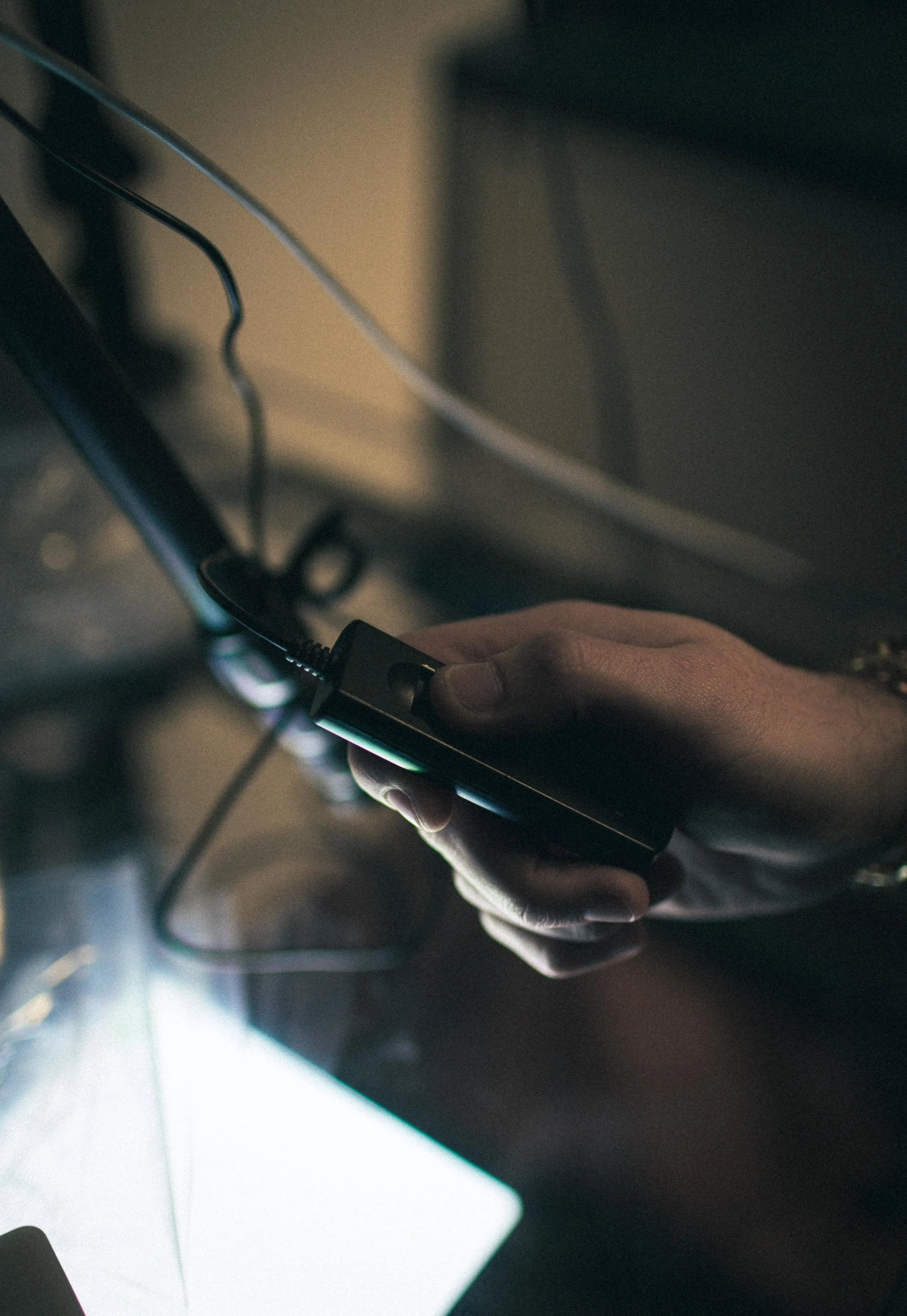 A person holding a smartphone with a charging cable plugged in.