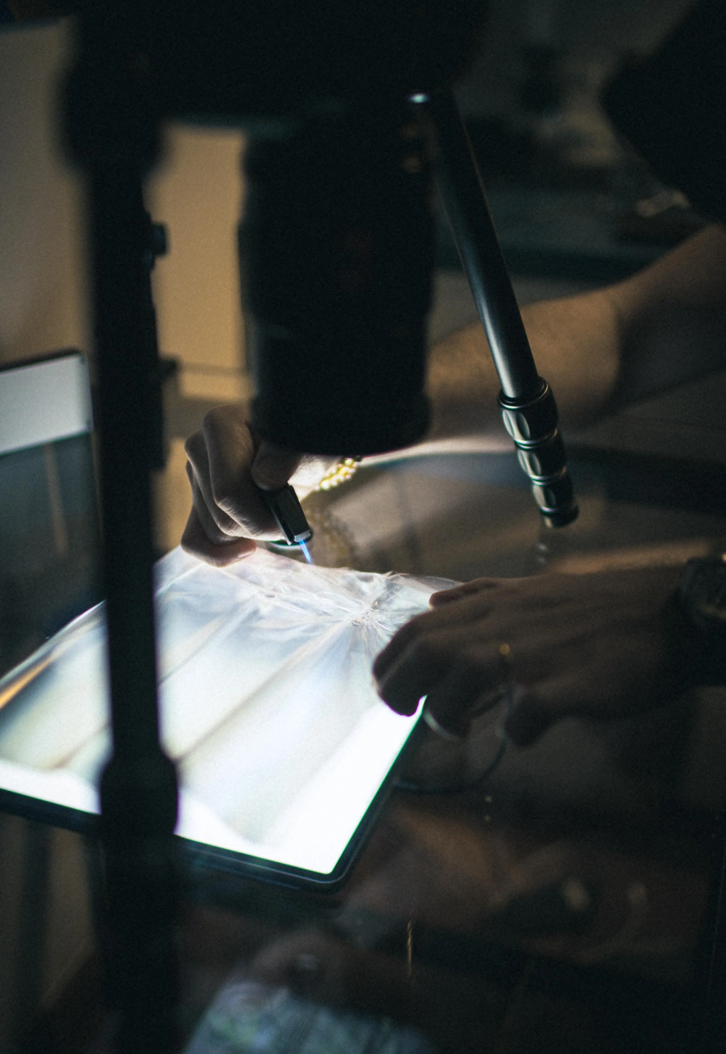 A person using a microscope connected to a tablet in a laboratory setting.