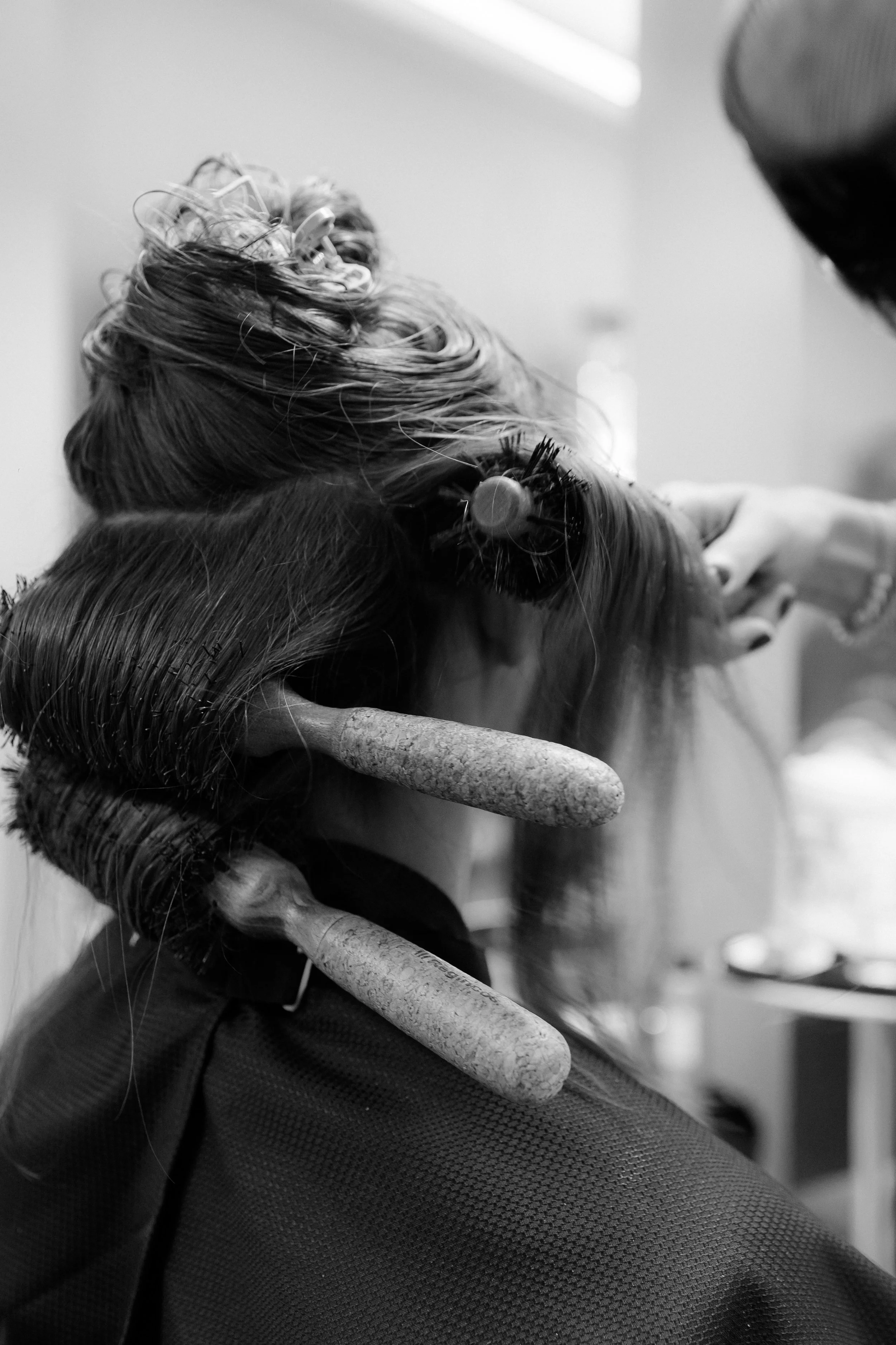Nahaufnahme einer Person beim Friseurbesuch, die Haare schneiden lässt, mit Friseurschere und Kamm.