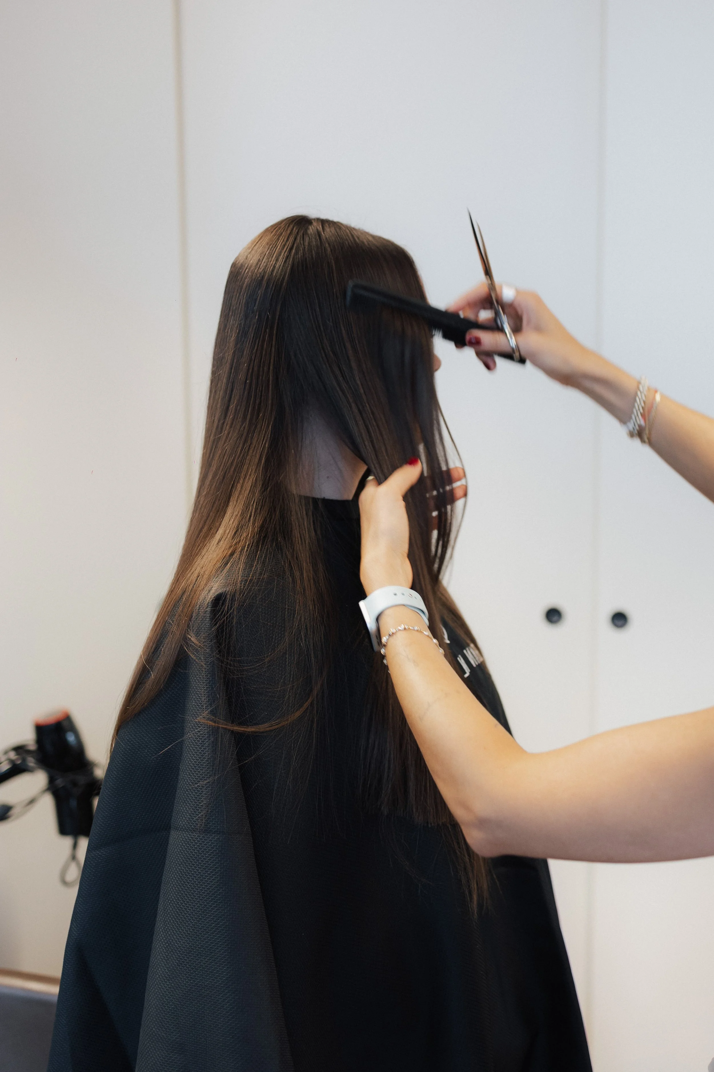 Frau bekommt Haare geschnitten, Friseurin schneidet die Haare einer Kundin in einem Salon.