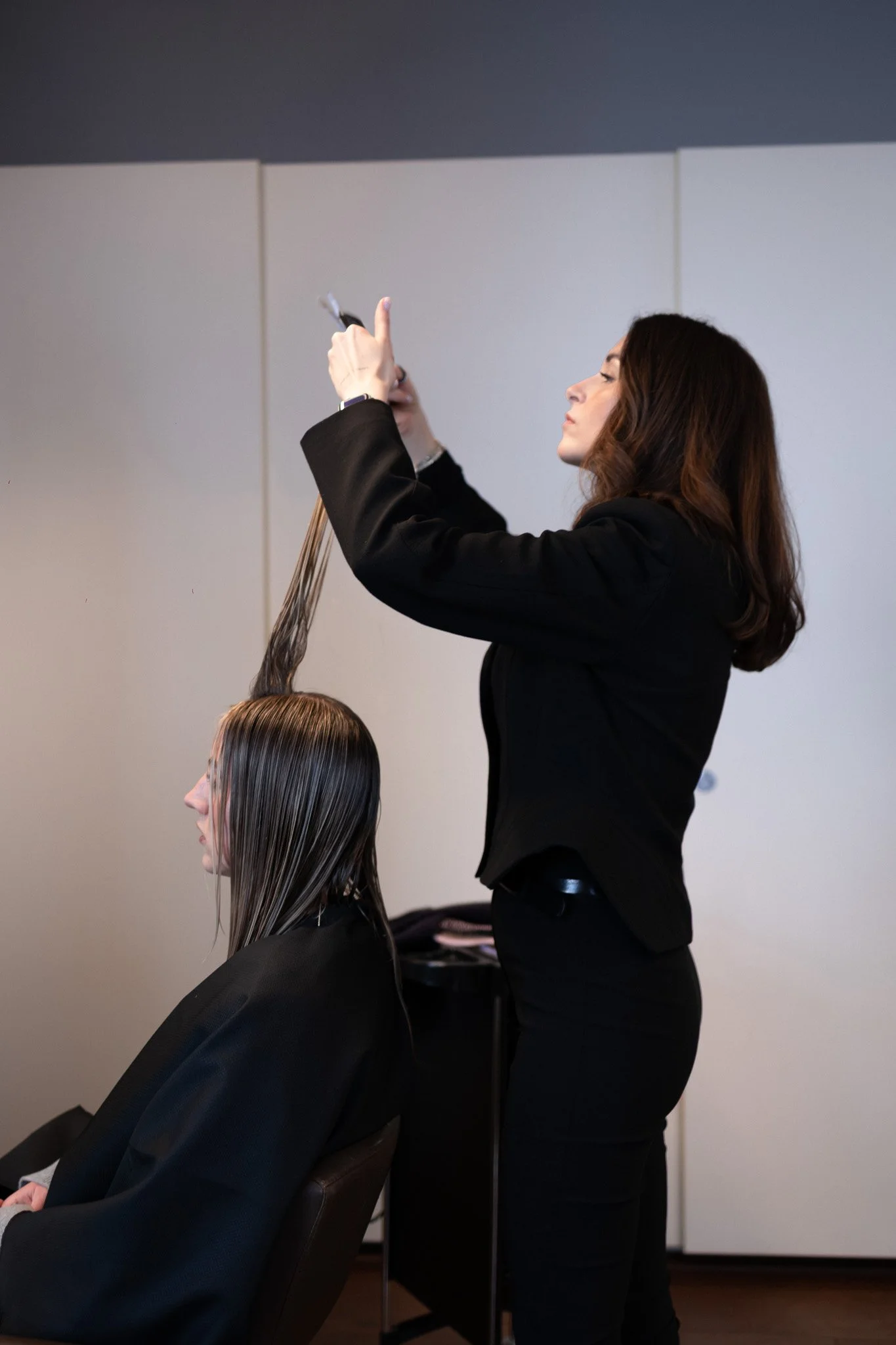 Eine Friseurin stylt das Haar einer Dame in einem Friseursalon.