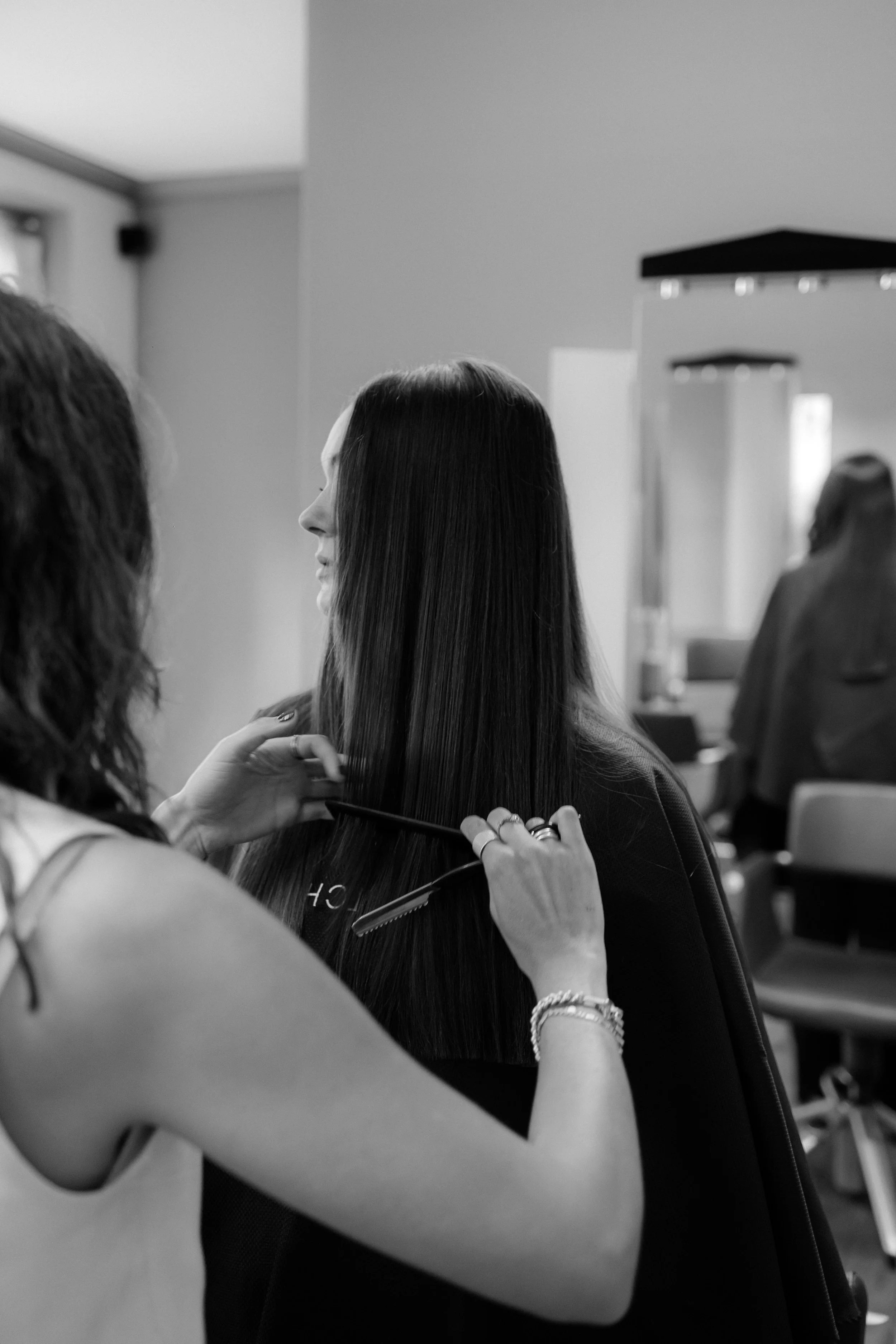 Friseur schneidet langem dunklen Haar einer Frau in einem Salon.