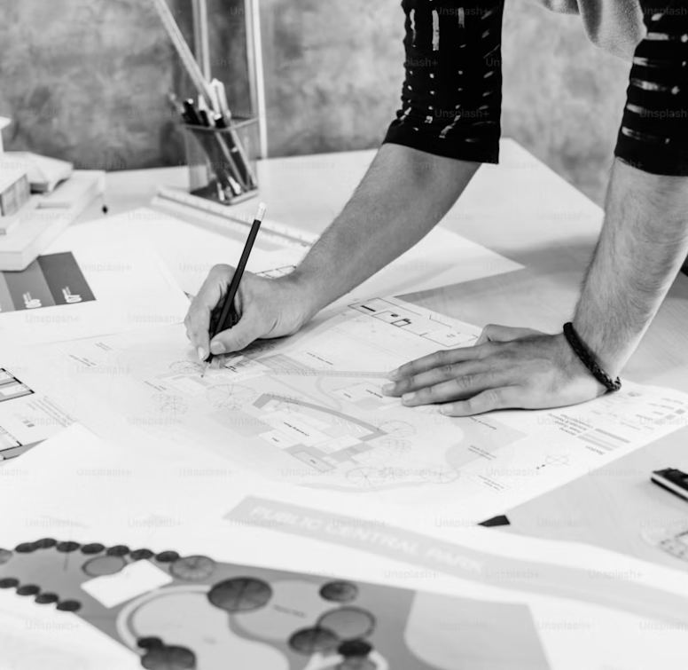 A landscape designer working on a garden design plan with drawings and concept materials.