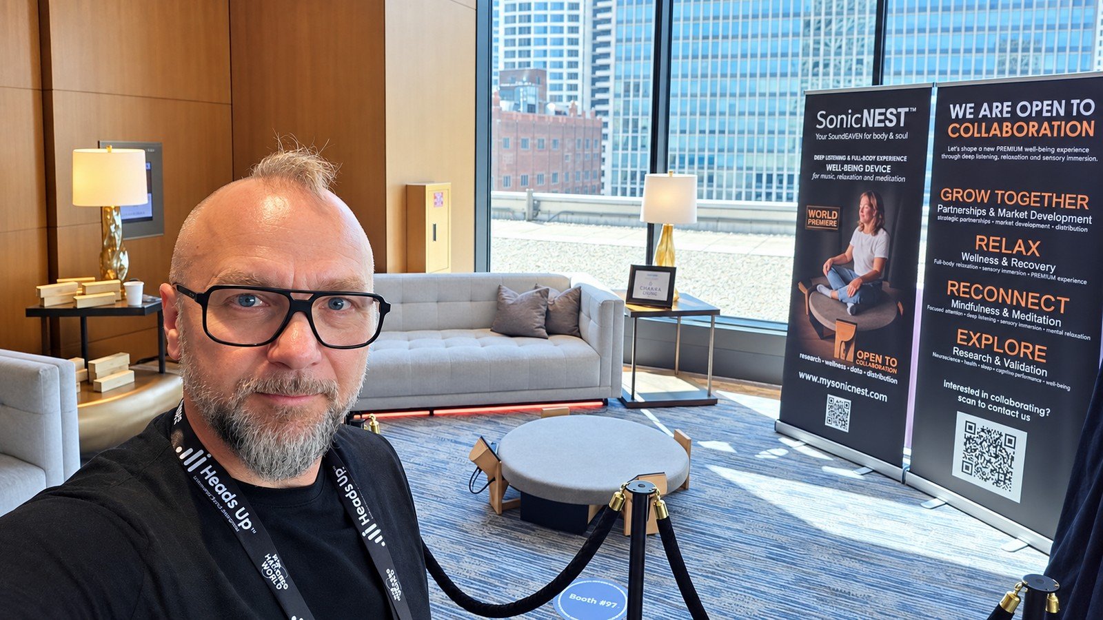 Founder and designer of SonicNEST Tom Fechter at Biohackers World Chicago 2026 during the SonicNEST™ world premiere inside the VIP Lounge with city skyline and project banners.