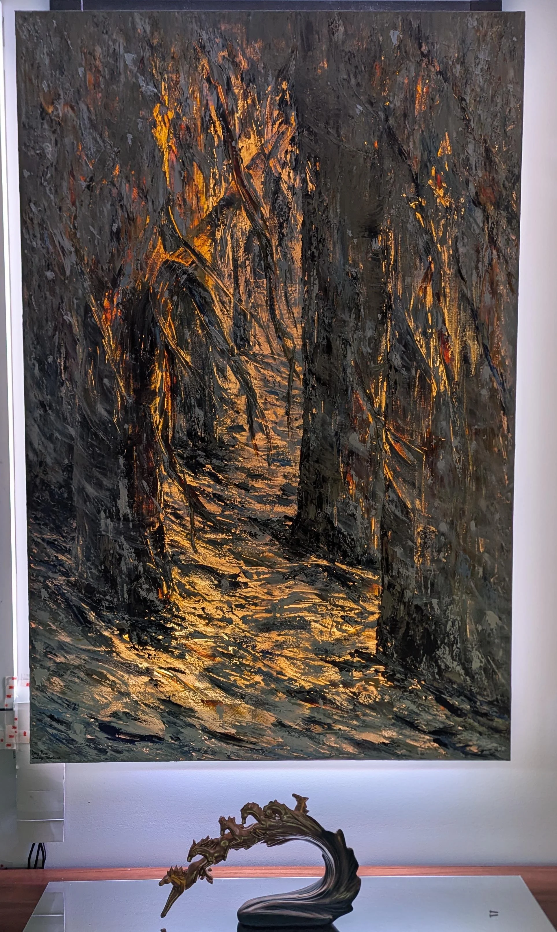 An abstract painting on a large canvas displays dark, textured strokes with hints of warm yellow and orange lighting. In front of the painting, there is a stylized sculpture of a horse on a stand, shaped with flowing lines and intricate details.