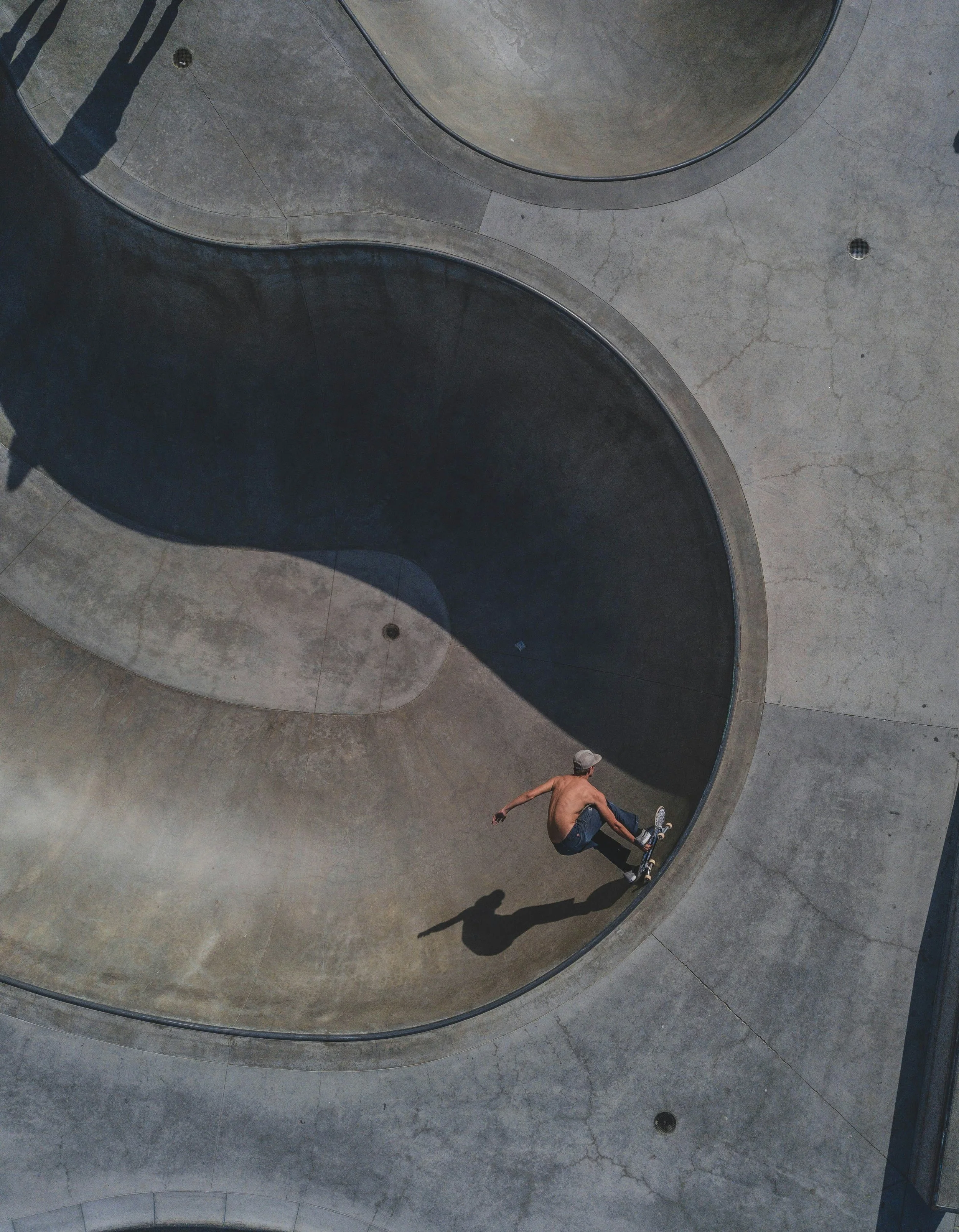 Ein junger Mann mit T-Shirt, Jeans und Mütze fährt auf einem Skateboard in einem zylindrischen Skatepark.