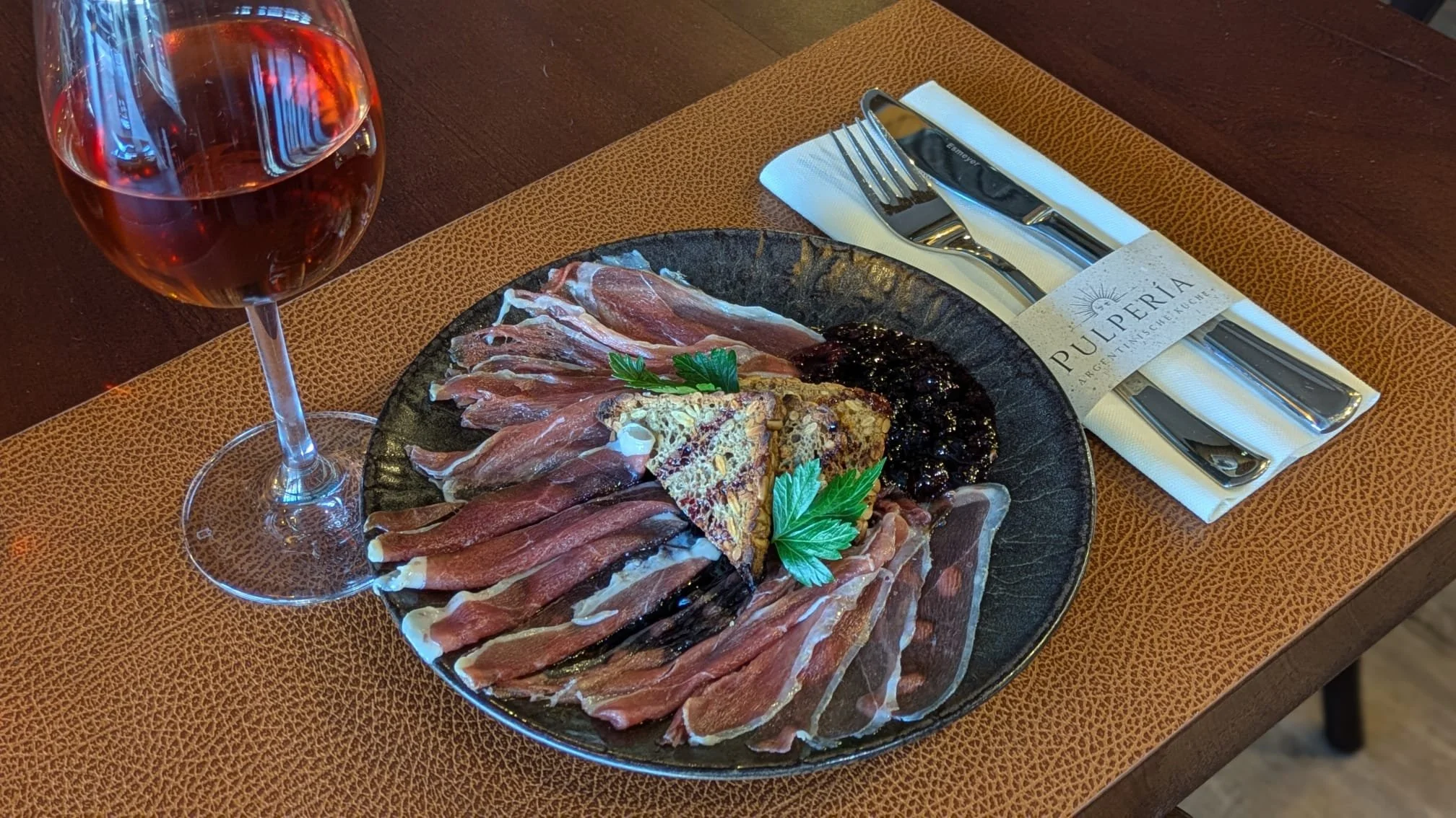 Carpaccio de Pato: hauchdünn geschnittene Entenbrust mit Weingelee und Körnerbrot, dazu ein Glas Rosé