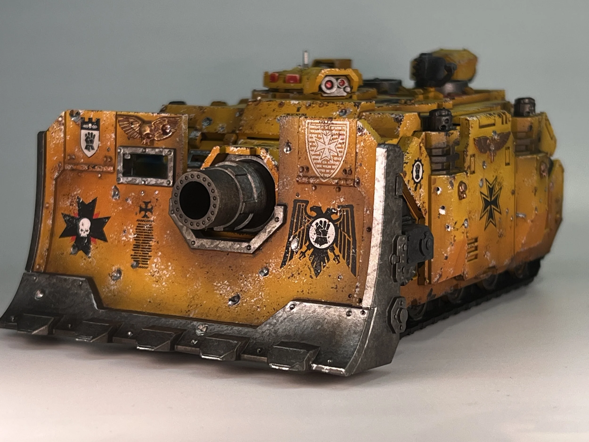 Close-up of a yellow painted miniature tank with weathering and decals, displayed on a flat surface.